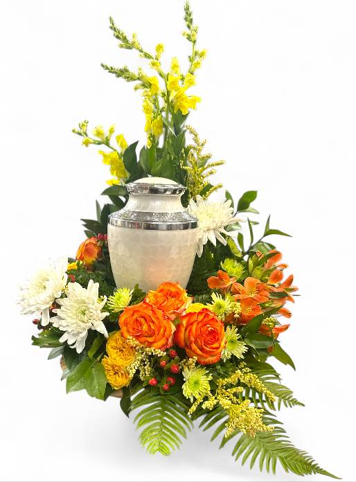Summer Memories Memorial Urn (Round)  - This vibrant sympathy arrangement, thoughtfully presented in an 8-inch design tray, offers a heartfelt tribute filled with warmth and beauty. A foundation of lush foliage, including variegated pittosporum, sword fern, ming fern, eucalyptus, and lily grass, creates a harmonious backdrop that enhances the floral display. Cheerful yellow snapdragons stand tall, symbolizing strength and grace, while four lively stems of green button poms add a playful touch. Stems of orange spray roses bring bursts of color, representing admiration and joy, complemented by bright yellow alstroemeria, which express friendship and devotion. The addition of solidago stems adds a touch of golden warmth, alongside red hypericum stems, symbolizing protection and encouragement. Striking green spider mums offer a unique elegance, and bi-colored orange roses complete the arrangement, embodying a vibrant spirit and the beauty of cherished memories. Together, these flowers convey a message of love, comfort, and remembrance during this poignant time. Urn not included.