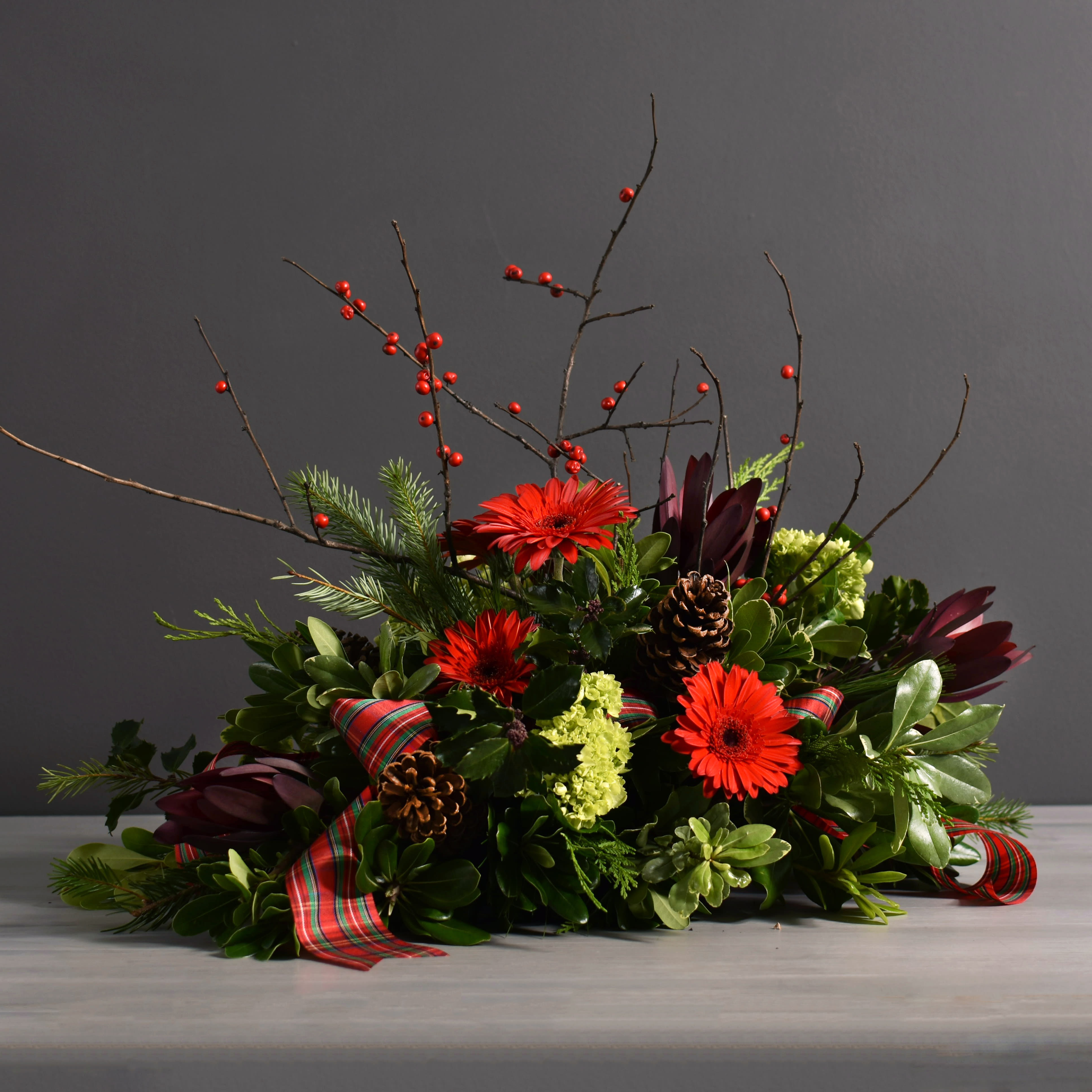 Gertrude - Wild winterberry, green hydrangea and red gerbers mixed with loose holiday greens and pine cones