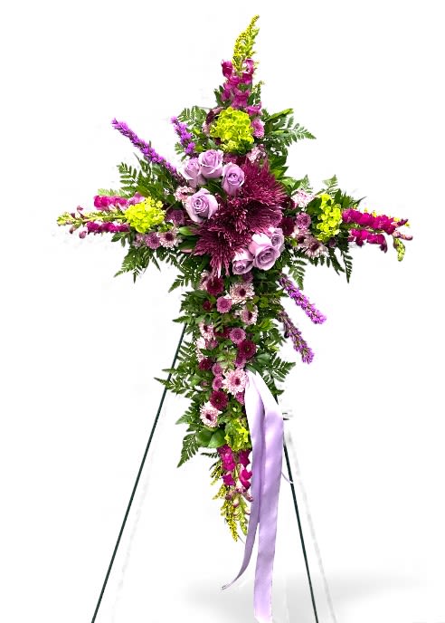 Purple and Lavender Easel - This purple and lavender easel features a graceful cross-shaped display, beautifully adorned with an array of soft lavender and purple blooms. Elegant roses, lush spider mums, and delicate daisy-like flowers are accented by vibrant chartreuse buds and fresh greenery, creating a harmonious blend of color and texture. Cascading stems and a flowing lavender ribbon add an extra touch of movement and sophistication, making this arrangement a heartfelt symbol of peace, remembrance, and serenity for any memorial or celebration of life.