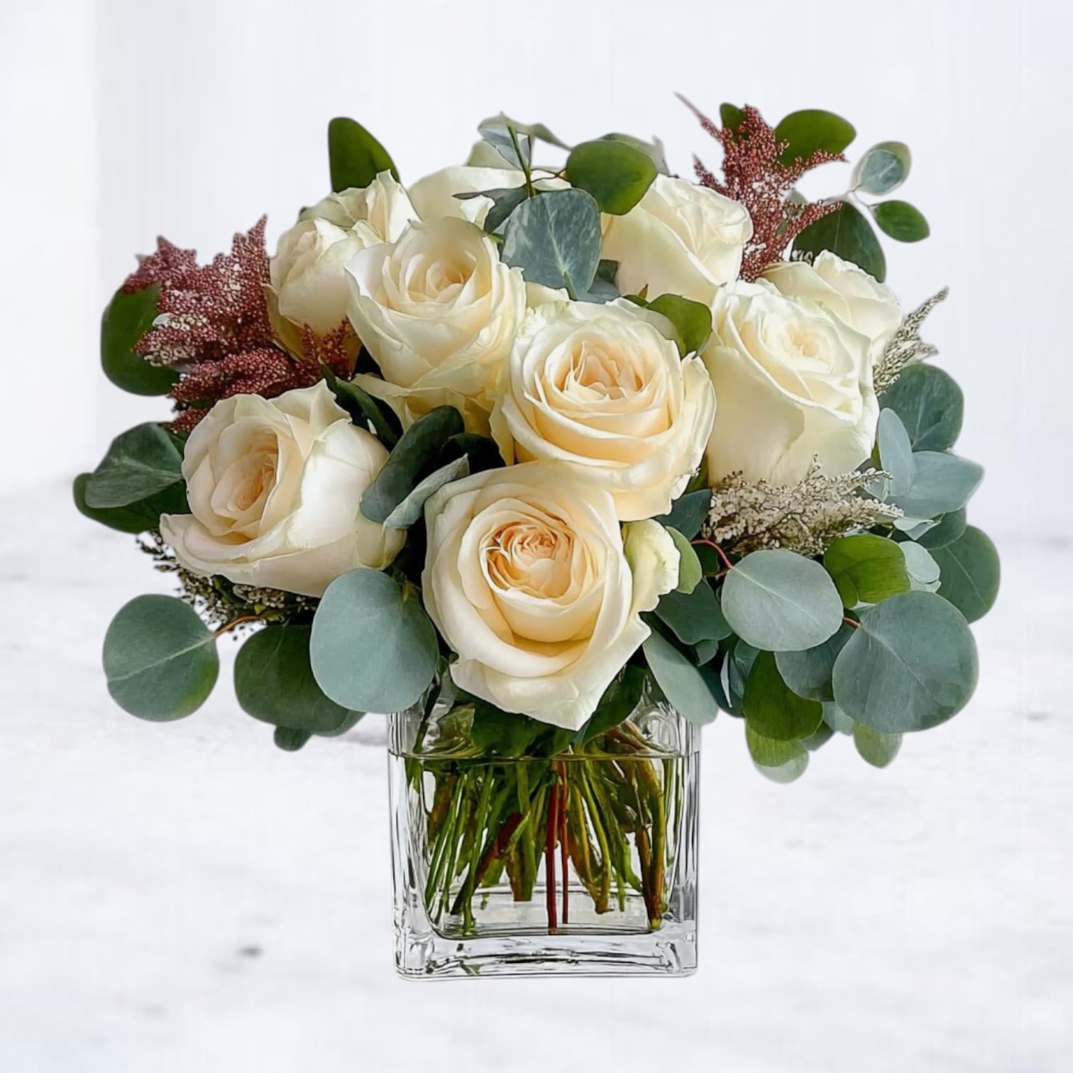 Flourish &amp; Frond - Elegant and effortlessly refined, the Flourish &amp; Frond arrangement features pristine white roses nestled in a bed of lush eucalyptus and curated foliage. Designed in a modern white cylinder vase, this timeless composition brings a sense of calm sophistication to any space. Perfect for sympathy gestures, minimalist weddings, or moments that call for pure, graceful beauty. With its soft palette and organic textures, it's a floral statement that quietly speaks volumes.