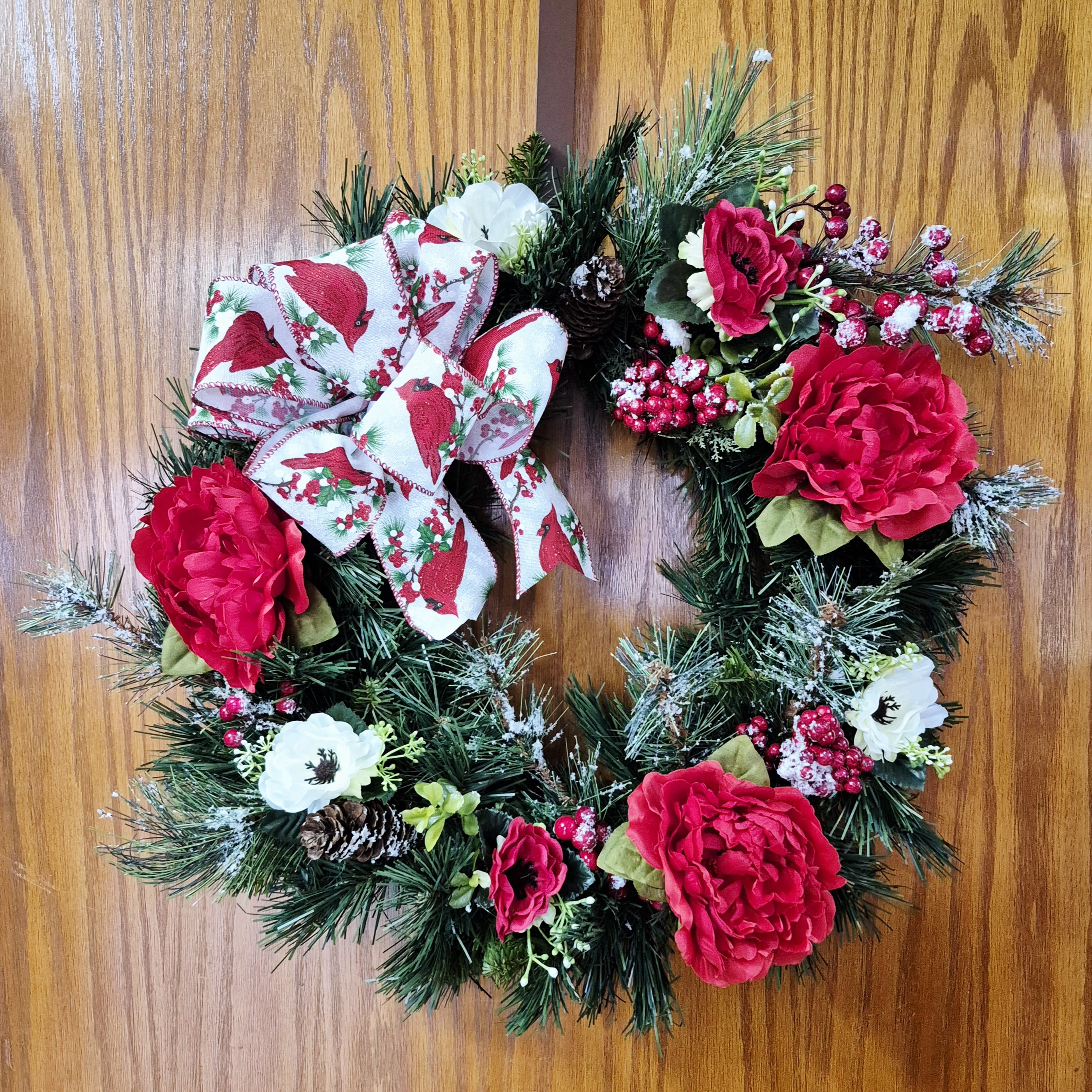 Red Cardinal Christmas Wreath - This beautiful silk Christmas wreath is the perfect accent to your front door or your Christmas wall decor! Made on a 18 inch pine wreath with white and red flowers, flocked pine and a beautiful red cardinal bow. 