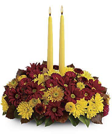 Harvest Happiness Centerpiece's - Happy yellow mums and a golden taper candle bring sunshine to your Thanksgiving dinner table. Lovely as a Thanksgiving centerpiece or stylish seasonal décor anywhere in the house, the burgundy and yellow fall flowers look especially rich mixed with brown copper beech leaves. Red matsumoto asters and a variety of burgundy, yellow and bronze mums are accented with green salal and brown copper beech leaves. A cheerful yellow taper candle glows above it all. Orientation: All-Around