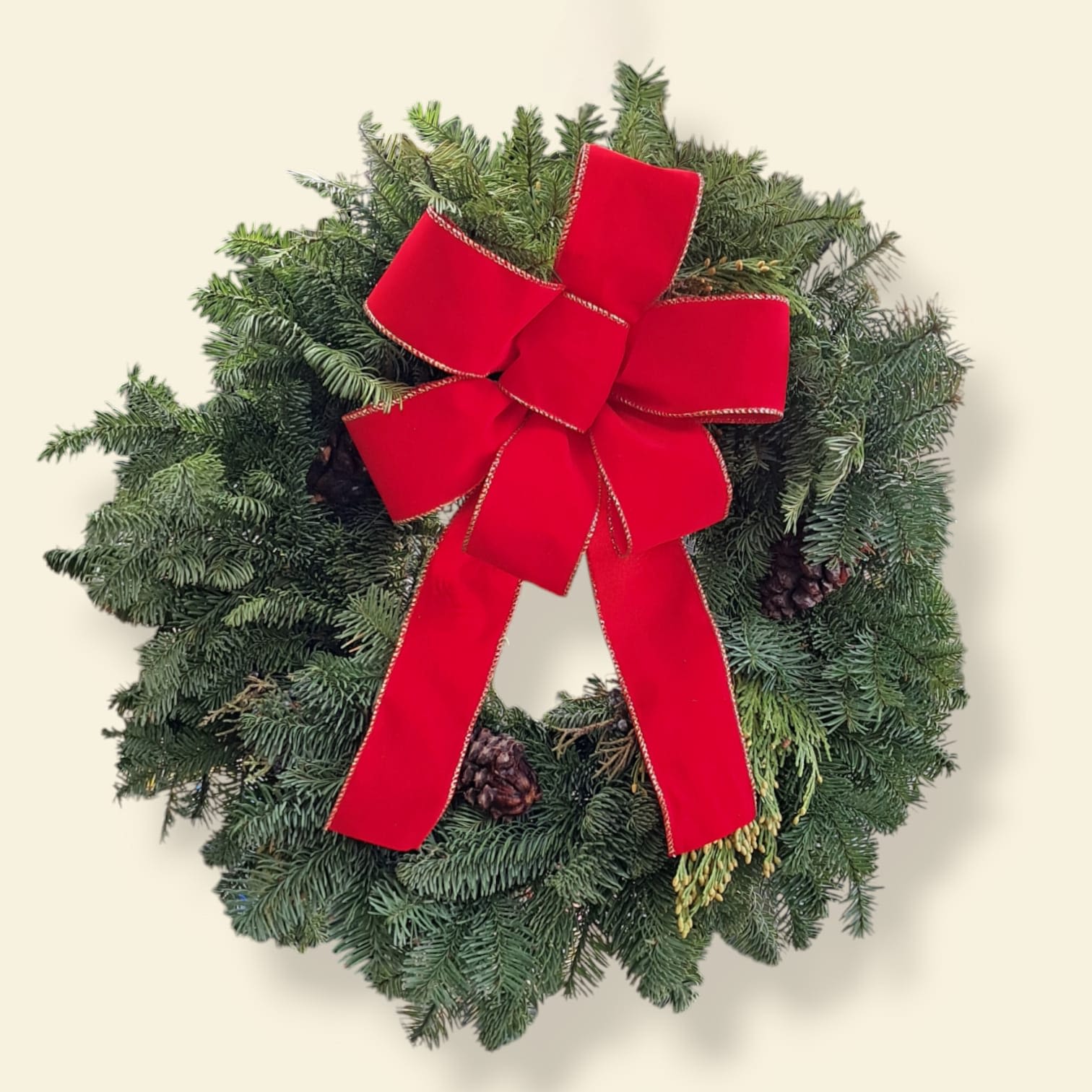 Red Bow Wreath - This wreath is adorned with pinecones and a big red bow.