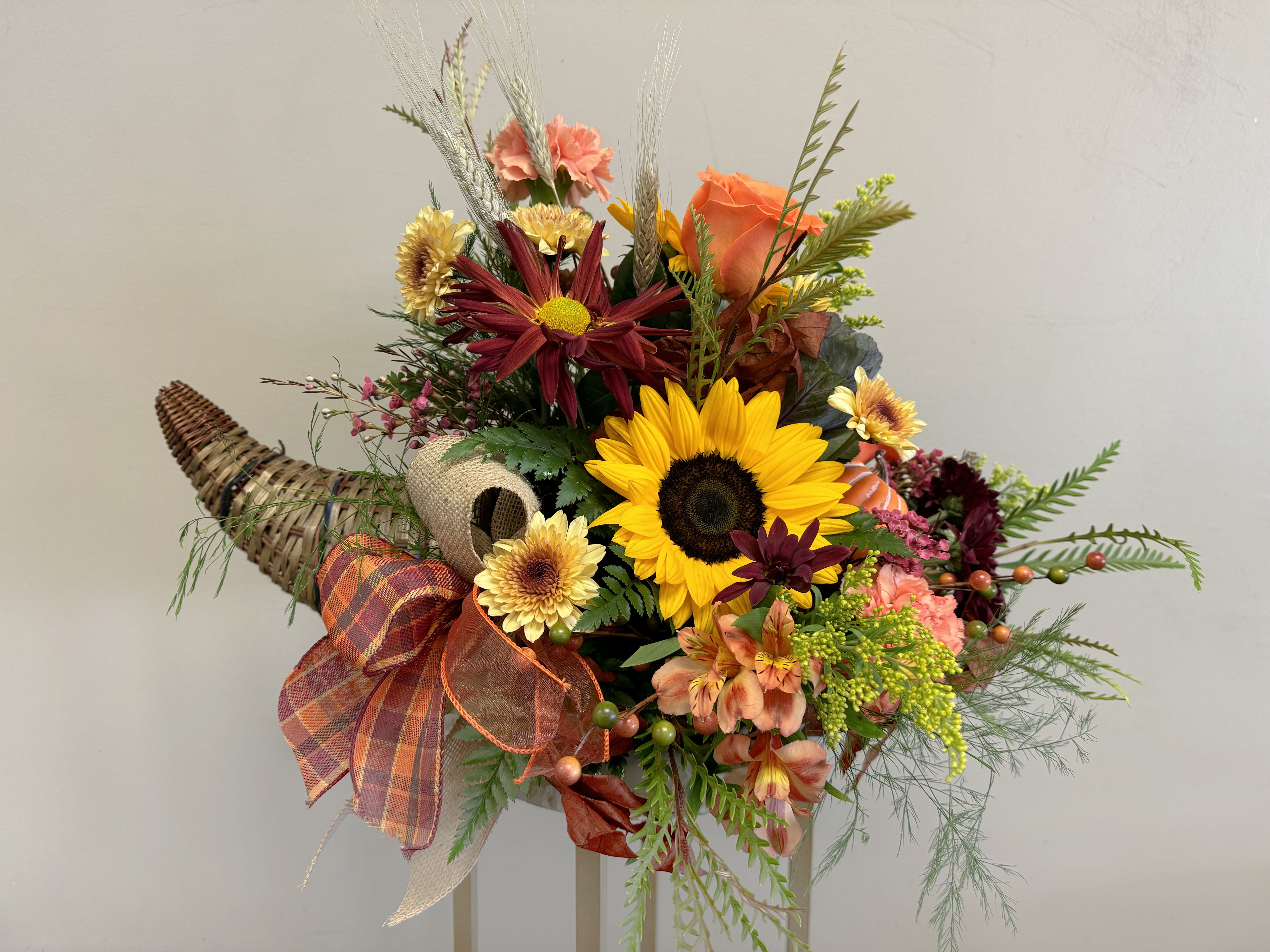 Designer's Choice Autumn Cornucopia  - Embrace the warmth and beauty of the season with our Autumn Abundance Cornucopia! This abundant arrangement, hand-crafted right here in Goodyear, Arizona, features the freshest autumn blooms like vibrant sunflowers, rich orange roses, and golden mums, nestled among fall leaves and rustic accents. Arranged in a charming, woven cornucopia, this stunning centerpiece is perfect for Thanksgiving gatherings or adding seasonal décor to your home. 