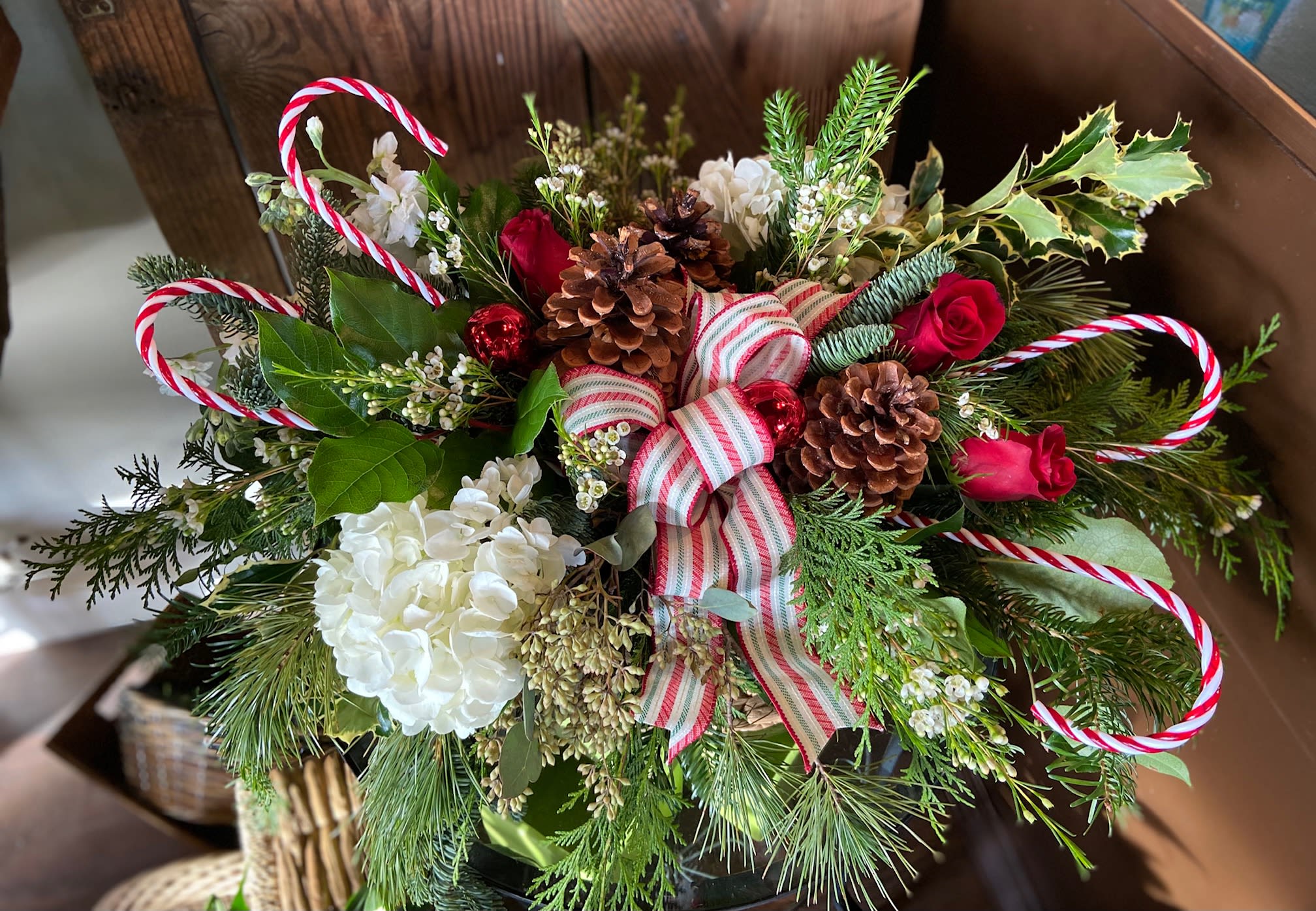 Candy Cane Dreams - Fun and Festive Centerpiece for the Family or Young at Heart.  Assortment of Holiday Colored Blooms with Ribbons, Pinecones, and Candy Canes.