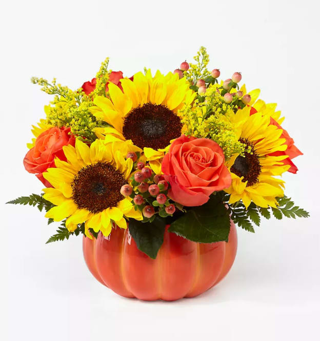 Pumpkin Flower Arrangement - An Arrangement of sunflowers, orange roses with seasonal greenery in a ceramic pumpkin shape container.