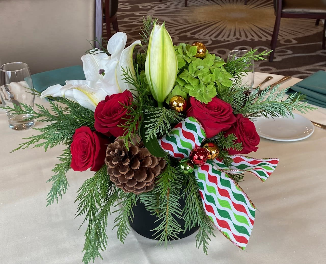 Festive Gatherings - Festive gatherings are what holidays are all about. This arrangement of fresh winter greens, red roses, and green hydrangea accented colorful ribbon is perfect for your Christmas or Kwanza celebration. 
