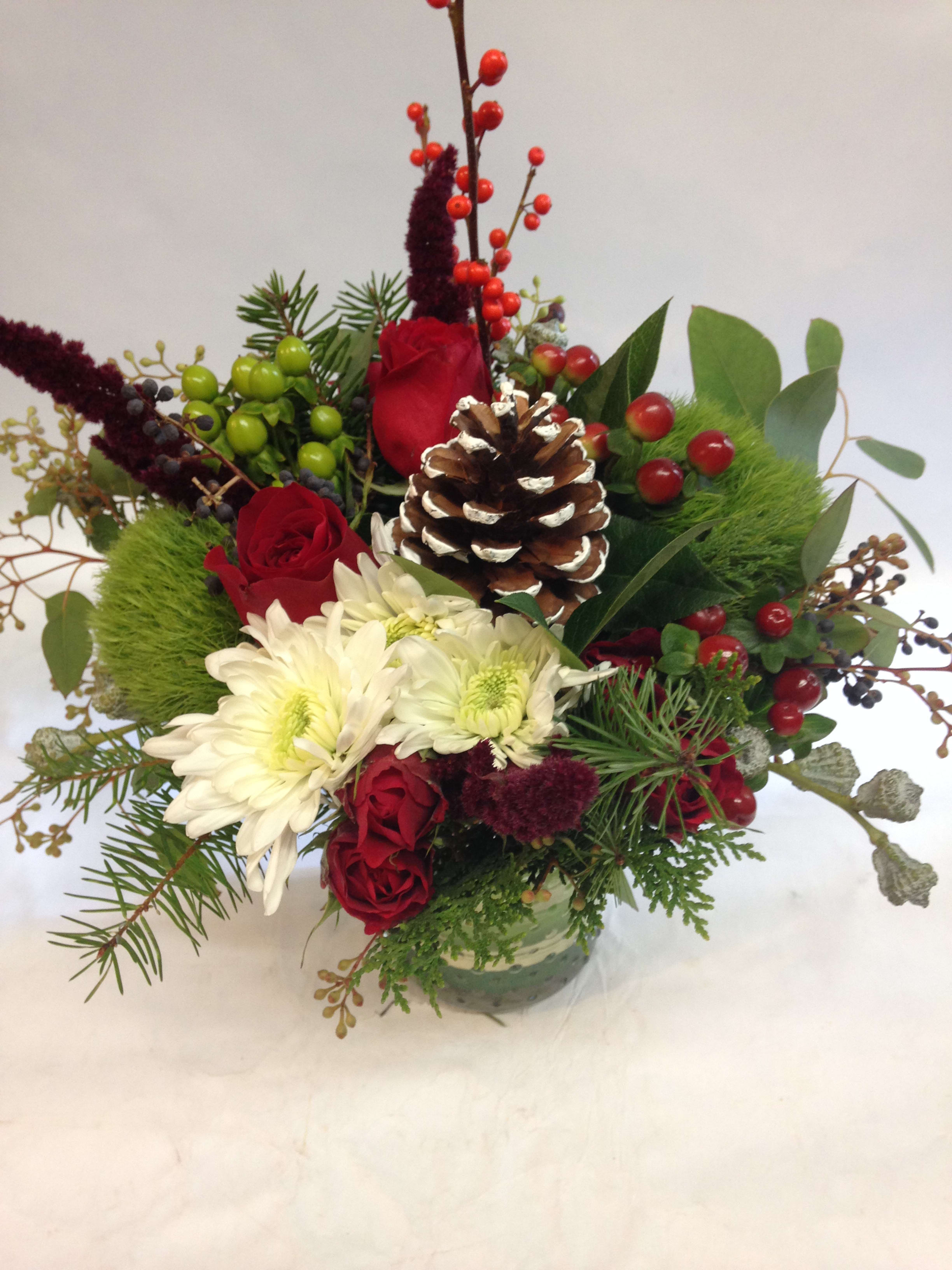 Festive Holiday Cheer Arrangement  - This darling arrangement is full of cheer for the holidays! Featuring white spider mums, red roses, and seasonal greens and filler.(Some flowers may be subject to change depending on the season. We will contact you with available flower substitutions; please contact us with specific questions if you are concerned with flower availability, thanks!) Featured Arrangement: $85.00