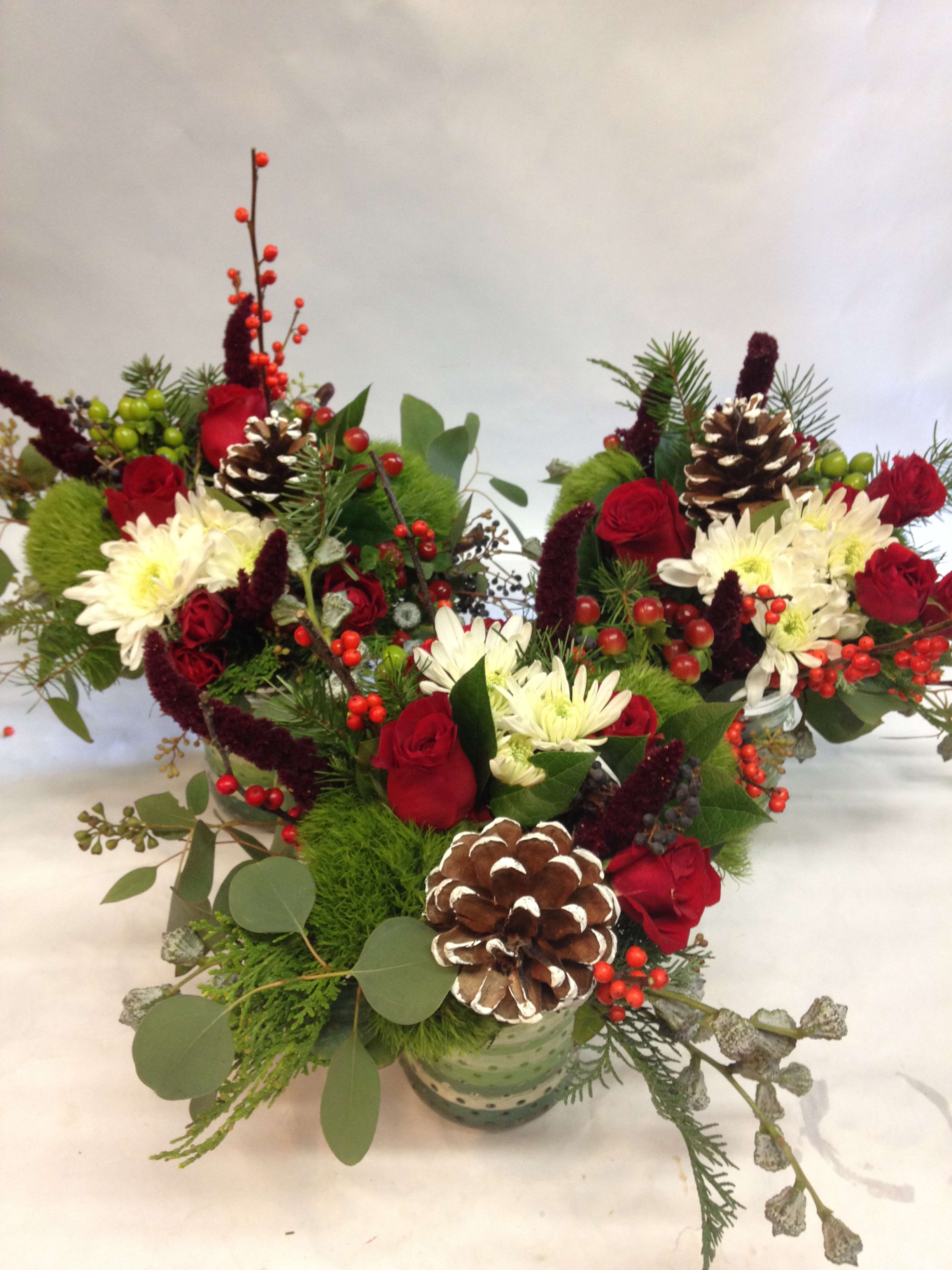 Festive Holiday Cheer Trio - A trio of centerpieice style arrangements for your holiday party or just to brighten up the home. Featuring white spider mums, red roses and seasonal greens and fillers. (Some flowers may be subject to change depending on the season. We will contact you with available flower substitutions; please contact us with specific questions if you are concerned with flower availability, thanks!) Featured Arrangements: $85.00 each; $255.00 for three