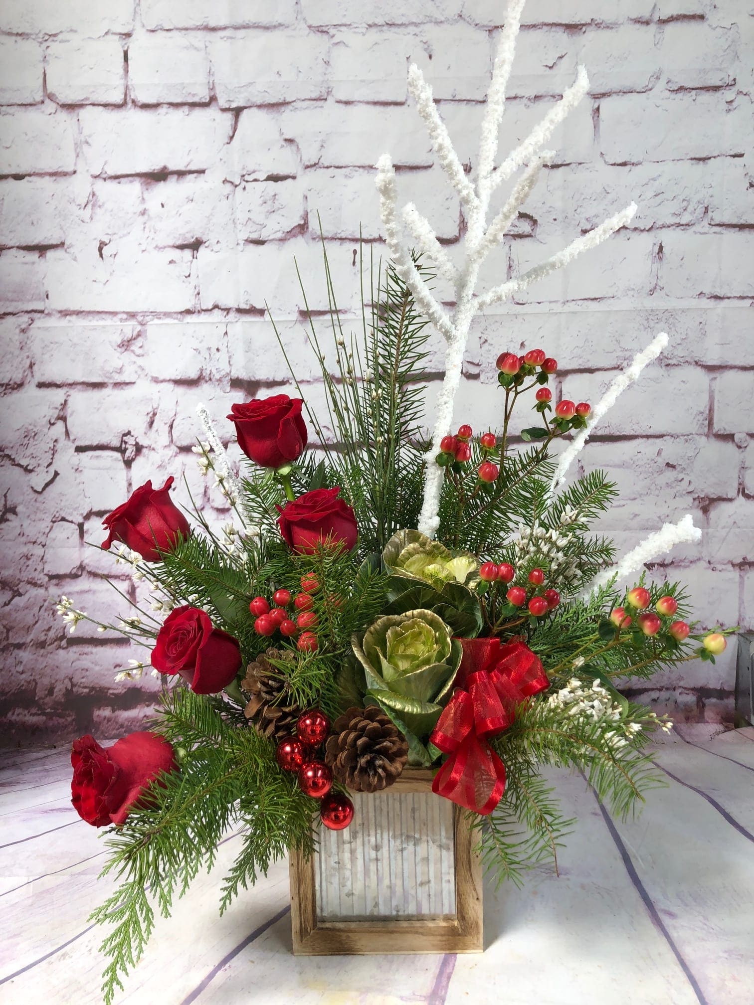 Woodland Christmas - Rustic box filled with winter greens, red roses, hypericum berries, white ginestra and flocked branches. Accented with ribbon, pine cones and glass balls. 