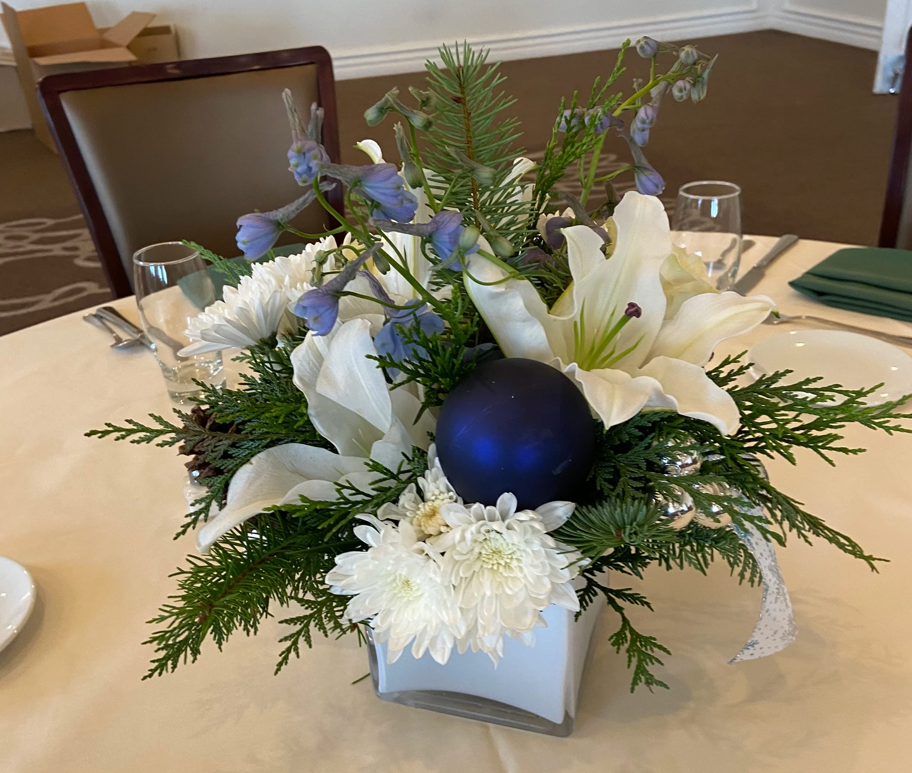 Hanukkah Joy - Traditional assortment of blue and white for you Christmas or Hanukkah table. Lilies, delphinium, chrysanthemum poms, and roses accented with winter greens.