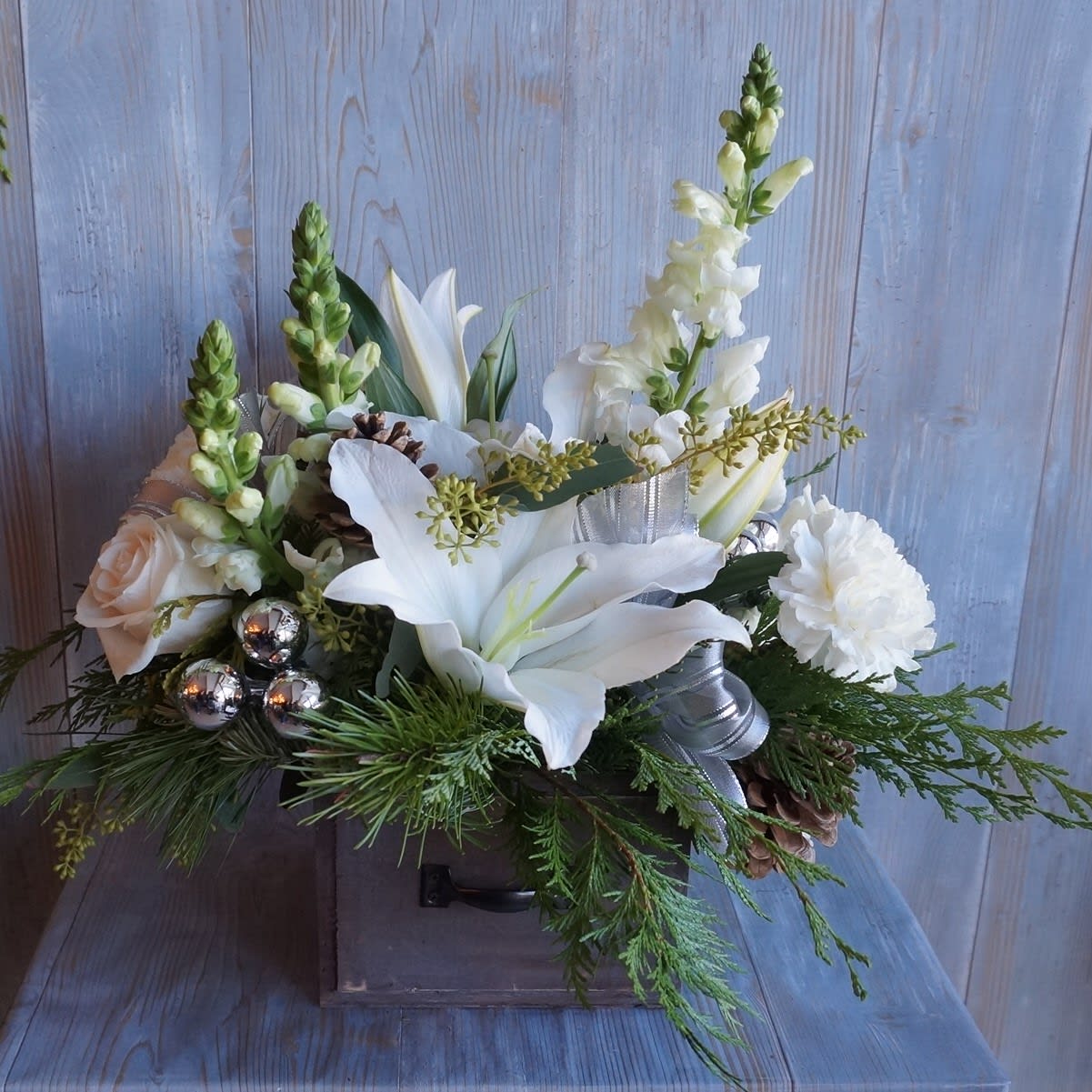 Holiday Lights Bouquet - All white flowers accented with fresh winter greens. Lilies, roses, carnations, and snapdragons make sure there's a white Christmas regardless of the weather. 