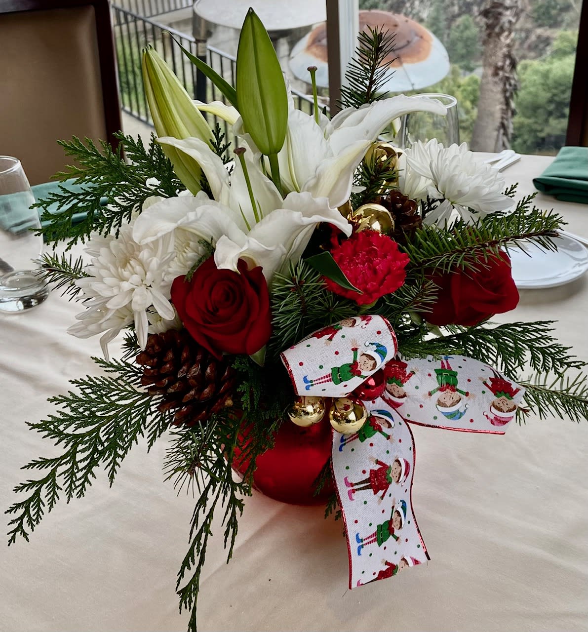 Jolly Christmas  - Festive arrangement with lilies, carnations, roses, and chrysanthemum poms accented with fresh winter greens and decorated with pine cones and shiny glass balls. Perfect!