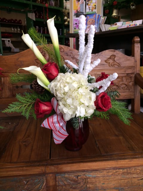 Peppermint Dreams - Classic red vase with white hydrangeas, red roses, calla lilies, winter branches and an assortment of winter greens accented with a peppermint ribbon treatment.