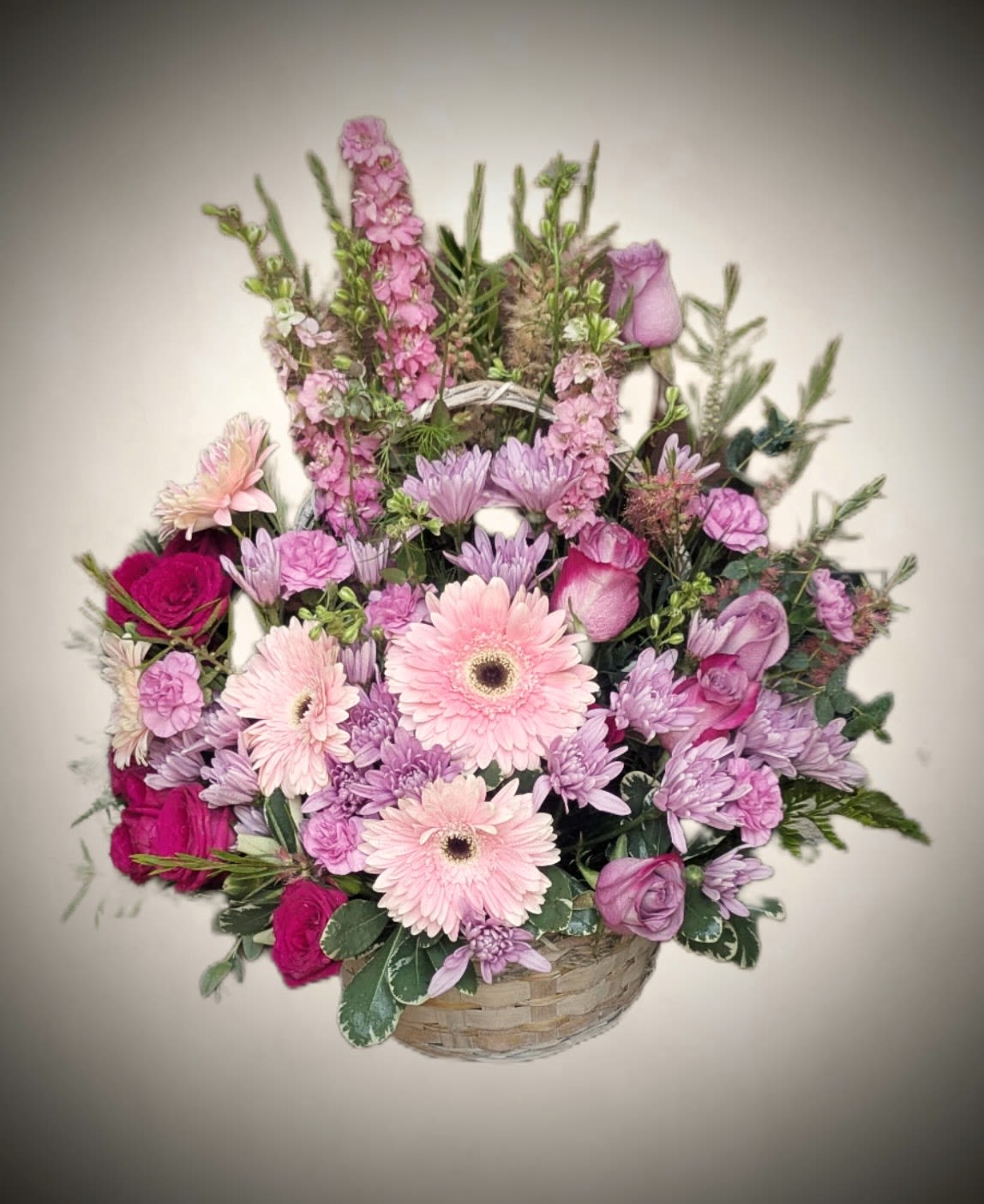 Pink Garden Basket  - Bright, elegant, and full of charm, this Pink Garden Basket features a lush blend of soft and vibrant pink blooms. The arrangement includes delicate gerbera daisies, roses, chrysanthemums, and accent flowers artistically arranged in a natural woven basket. With its graceful height and full, rounded shape, this design brings a touch of serenity and beauty to any space.  Perfect for birthdays, anniversaries, celebrations, or simply to brighten someone’s day, this fresh floral basket delivers a heartfelt message of love, joy, and appreciation.