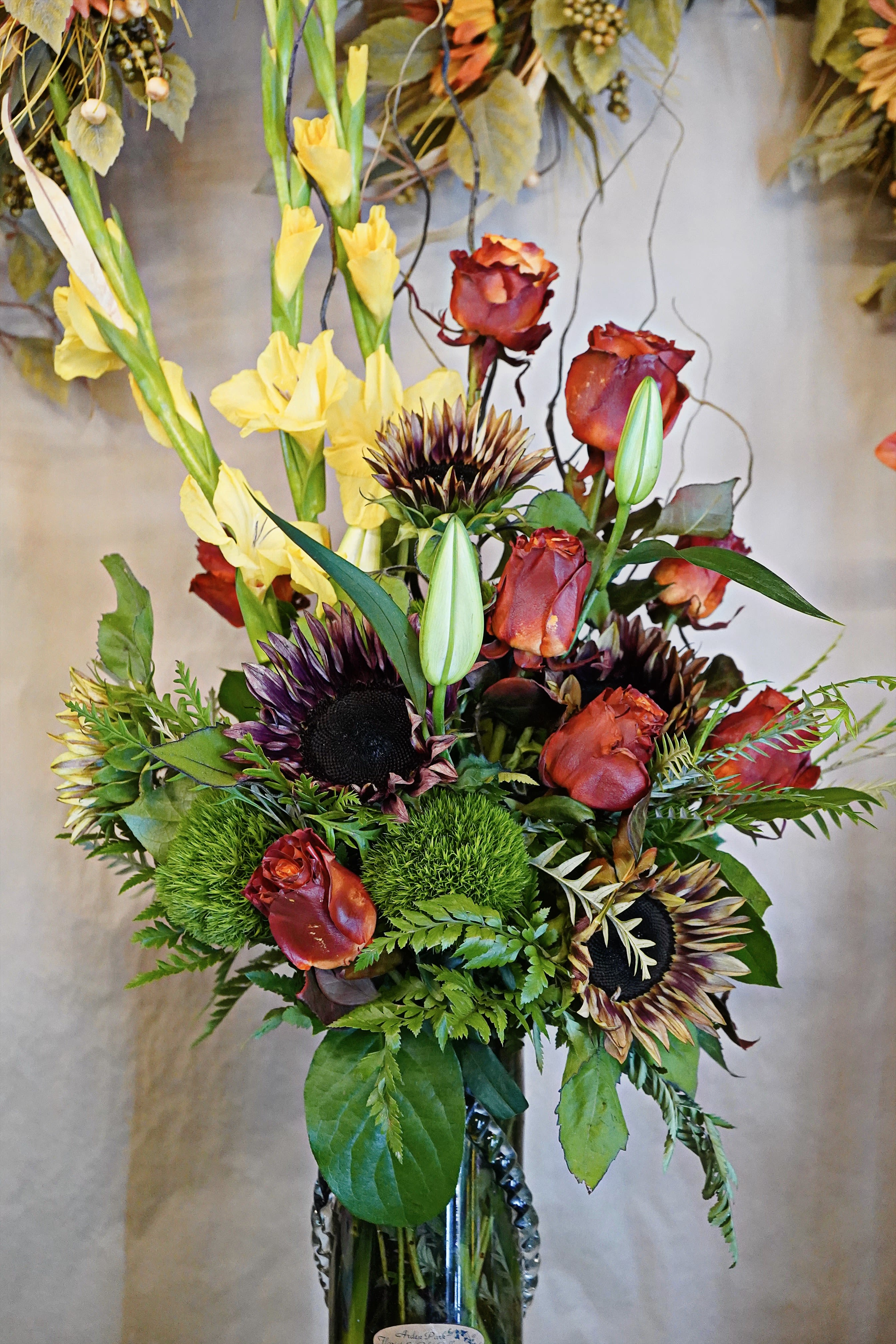 Rose Gold - With a dozen roses, multi colored sunflowers, and nova lux gladiolus this bouquet will define any space it occupies. 