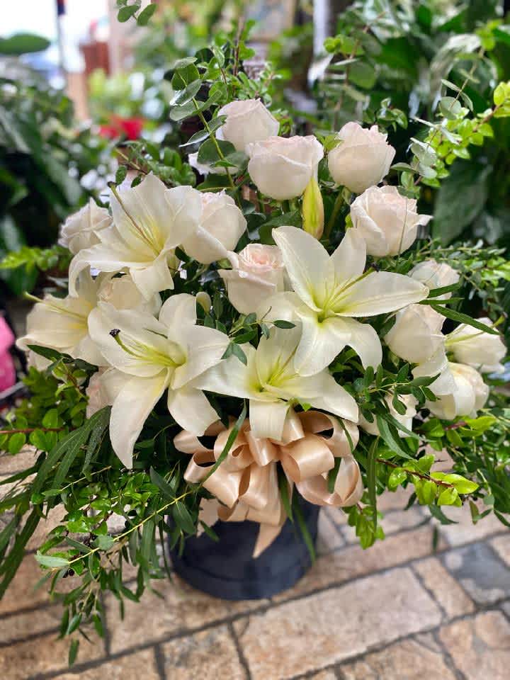 The Hamptons - The epitome of class and luxury with this over-the-top arrangement of gorgeous lilies and roses with a big bow to top it off! Arranged in a reusable decorative box. Just to let you know, flowers and containers may vary but we do our best to match the arrangement shown.  