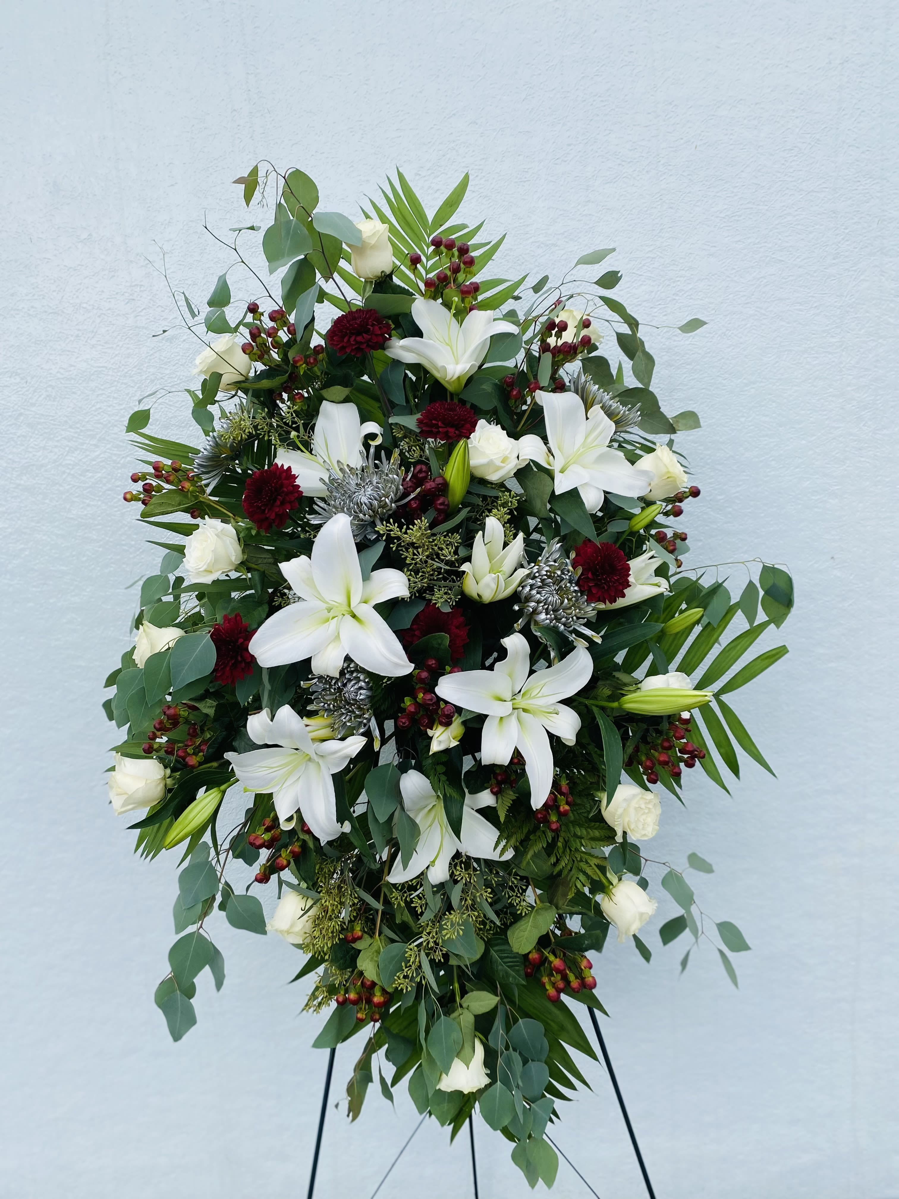 Crimson&amp; Ivory Remembrance  - This white and burgundy standing spray is a striking tribute that blends purity, love, and deep remembrance. Pristine white blooms symbolize peace and eternal rest, while rich burgundy flowers convey devotion, strength, and heartfelt admiration. Thoughtfully arranged with lush greenery, this spray creates a beautiful contrast that honors your loved one with dignity and grace. A timeless expression of respect, it offers comfort and a meaningful farewell.”