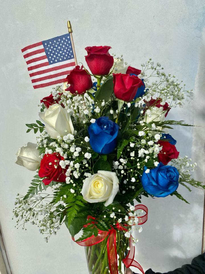 Thank You For Your Service - A patriotic array of a dozen roses. Accented with babies breath, an American Flag, and decorative ribbon. This arrangement includes painted roses. Perfect for any veteran or service member! Just to let you know, flowers and vases may vary but we do our best to match the arrangement shown.  