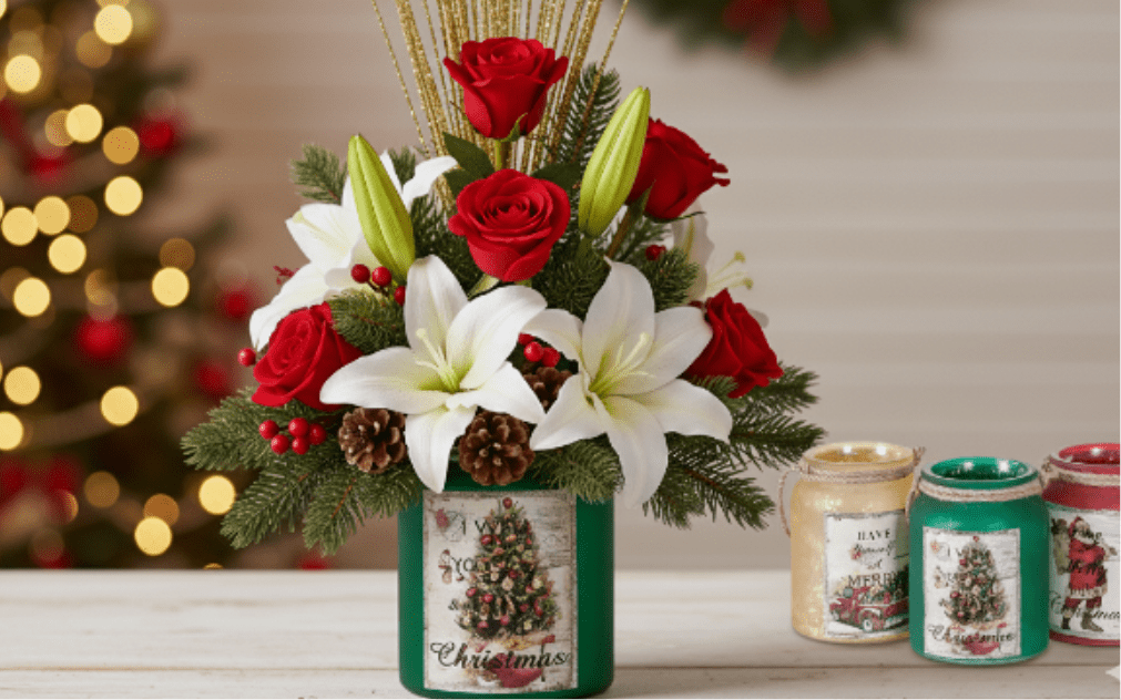 Holiday Vintage Jar Bouquet - Container may vary:  Celebrate the sounds and sights of the season with this charming, tradition-filled arrangement. The centerpiece features radiant red roses and elegant white lilies, complemented by fragrant evergreens, red berries, and natural pinecones. It is presented in a collectible  glass jar that showcases a nostalgic, vintage-inspired Christmas  Perfect for gifting or for adding a touch of sentimental Christmas spirit to any room.  Once the flowers fade, the keepsake jar can be reused as a candle holder or decorative holiday piece for years to come.