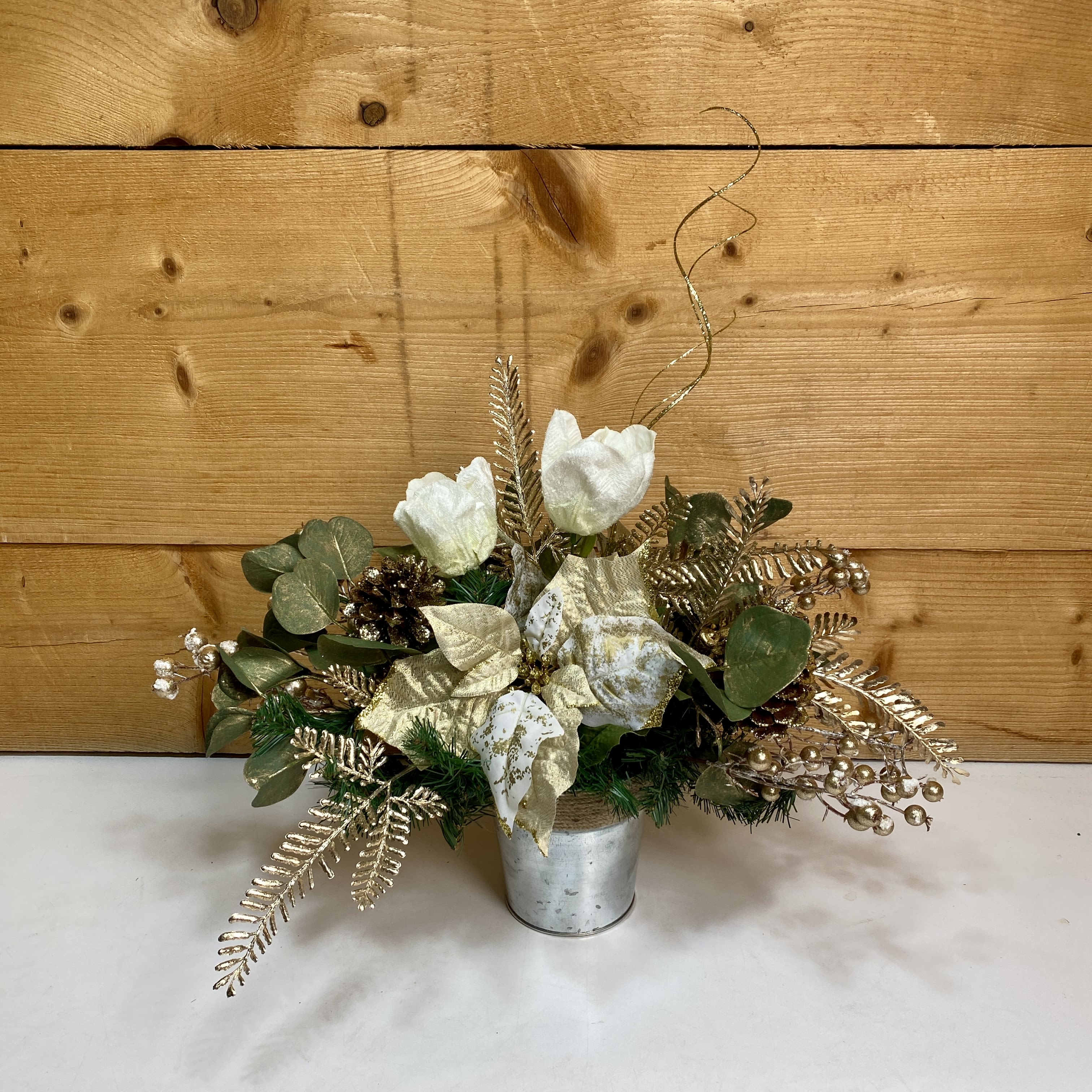 Tulip Tidings Silk Arrangement - Tulip Tidings Silk Arrangement is an artificial arrangement that brings an elegance to your winter decor. Featuring faux tulips, golden artificial poinsettias, and other golden winter accents in a tin container, this arrangement has a sophistication that can be enjoyed for many years.