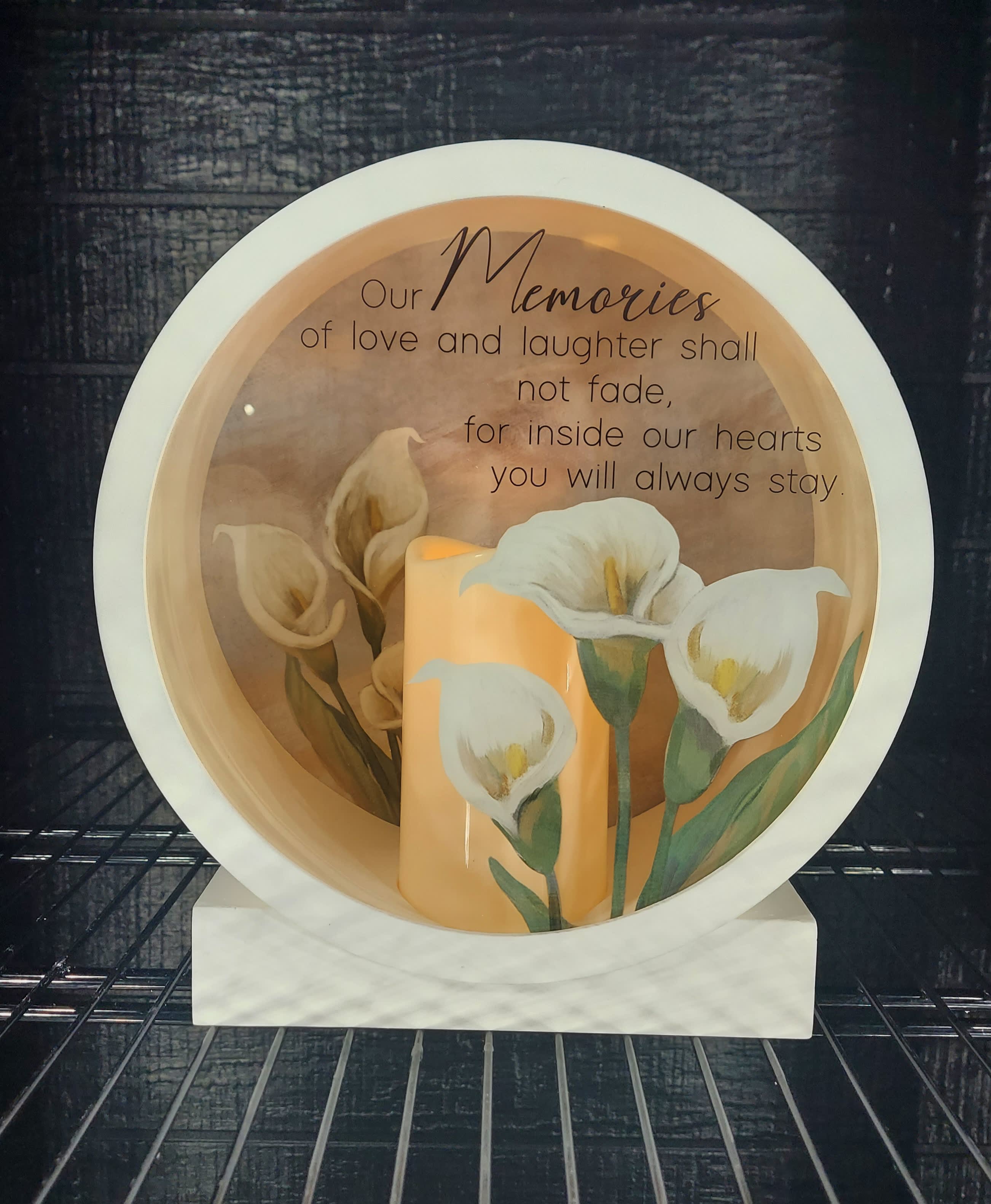 Our Memories Will Not Fade - A round shadow box, 10&quot; x 10.75&quot;, with a battery powered candle inside. Calla lilies are pictured on the glass front pane.and the back panel. Inscription: Our memories of love and laughter shall not fade, for inside our hearts you will always stay.