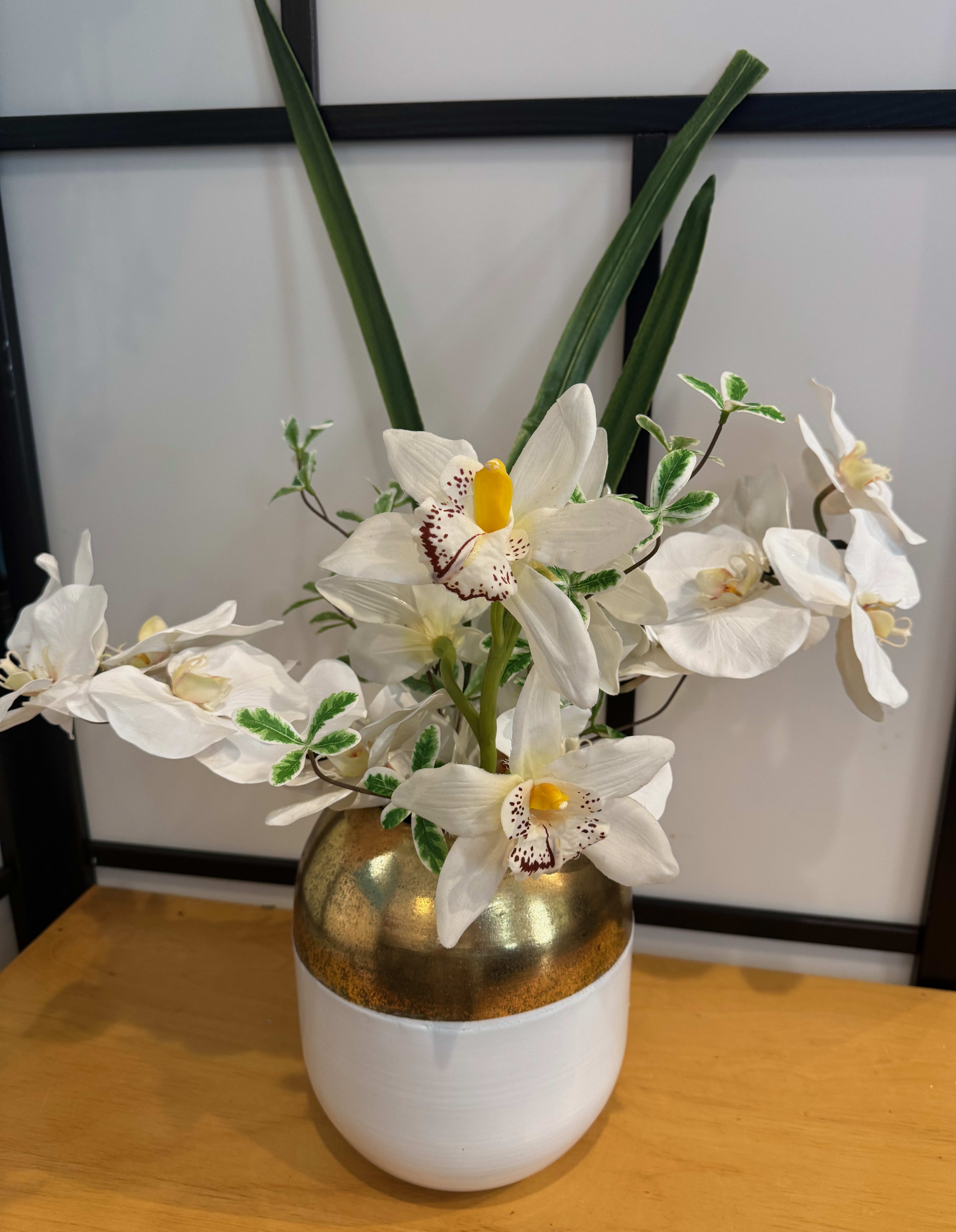 Stunning Orchids - You may order this arrangement with silk orchids as pictured, a plant in this container, or fresh cut orchid stems, (the most expensive). The wonderful things about orchids include their incredible diversity, striking beauty, and unique adaptations, There are two sizes in this unique gold and white vase. $30.00 and $50.00 vases. Please indicate any special colors or other specifics in the special instructions. 