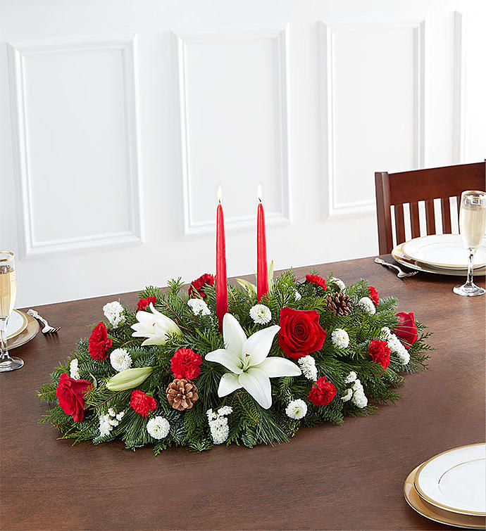 Traditional Christmas Centerpiece 90669M - Christmas is a time for celebrating with loved ones, and our traditional holiday table arrangement is at the center of that joy. Beautifully hand-designed with long-lasting blooms in the colors of the season, this fragrant centerpiece features long, red taper candles in the middle to cast a warm, cozy glow for all your guests.