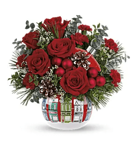 Holiday Village Ornament - All is calm, all is bright in the snowy village on this sweet ceramic ornament jar keepsake. Filled with a radiant Christmas bouquet, it's a joyful holiday showpiece in any home! Red roses, miniature white carnations and green button spray chrysanthemums are accented with noble fir, cedar and white pine. Delivered in a Snowy Village Ornament.