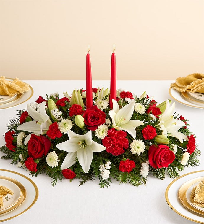 Traditional Holiday Centerpiece - Our classic table arrangement is an idyllic centerpiece for your Christmas celebration. Beautifully designed with long-lasting blooms in seasonal colors, this fragrant gathering features red taper candles to cast a warm, inviting glow throughout the holidays.