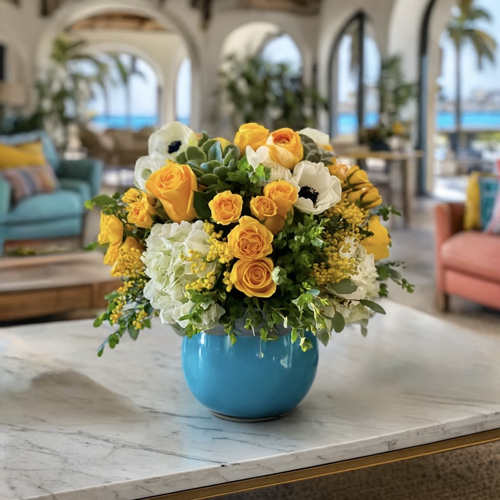Aruba - Brighten Any Space with Our Aqua Blue Spring Bloom Arrangement  Make a statement with this 7"x5" ceramic aqua blue container overflowing with the season’s most stunning flowers. Featuring a lush mix of ranunculus, tulips, anemones, roses, spray roses, succulents, and fresh seasonal greens, this arrangement blends vibrant color with timeless elegance.  Measuring approximately 13"x13" round, this floral centerpiece is perfect for spring celebrations, birthdays, Mother’s Day, or simply adding a touch of natural beauty to your home décor. Its refreshing aqua ceramic vase adds a modern yet soothing accent, making it as stylish as it is heartfelt.  Whether you’re sending love, celebrating a milestone, or refreshing your own space, this spring floral arrangement is sure to leave a lasting impression.