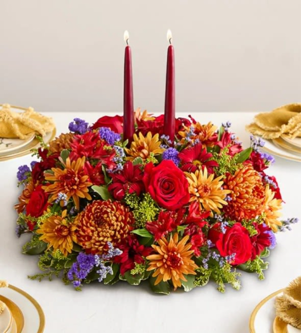 Brilliant Autumn Centerpiece - About Brilliant Autumn Centerpiece Set the table in brilliant style. Our centerpiece captures the rich beauty of autumn, with bursts of red, bronze, and purple amid assorted greenery. A burgundy taper candle stands at the center, ensuring a warm and welcoming ambience for every gathering. * All-around centerpiece arrangement with red roses, Peruvian lilies (alstroemerias), and daisy poms; bronze mum disbuds and  cushion poms; purple limoniums and statices; and solidago, accented with assorted greenery * Large arrangement features two 12&quot;H burgundy taper candles; measures approximately 12&quot;Dia * Medium arrangement features one 12&quot;H burgundy taper candle; measures approximately 11&quot;Dia * Small arrangement features one 12&quot;H burgundy taper candle; measures approximately 10&quot;Dia * Our florists hand-design each arrangement, so colors, varieties, and container may vary due to local availability * To ensure lasting beauty, Peruvian lilies may arrive in bud form and will fully bloom over the next few days