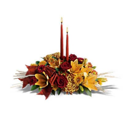 Graceful Glow Centerpiece - Add a graceful glow to your Thanksgiving dinner table or fall-decorated foyer with this warm, seasonal arrangement. Lilies, mums and asters are accented with sprays of wheat below glowing taper candles. This classic Thanksgiving centerpiece features orange asiatic lilies, red matsumoto asters, bronze disbud mums, bronze daisies and bronze cushion mums. Burgundy satin ribbon, stems of wheat, and two taper candles add seasonal sophistication. Orientation: All-Around