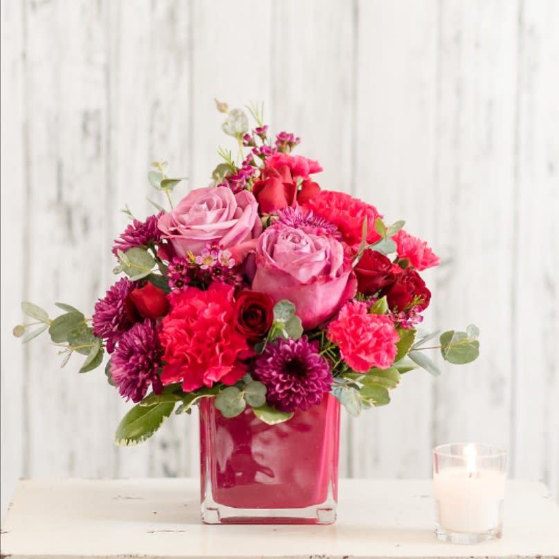 Beloved - Romantic blooms in magenta, lavender and red are classically arranged in a modern cube vase. Perfect for an end table or desk!   Approximate Size: 11&quot; H x 9&quot; W