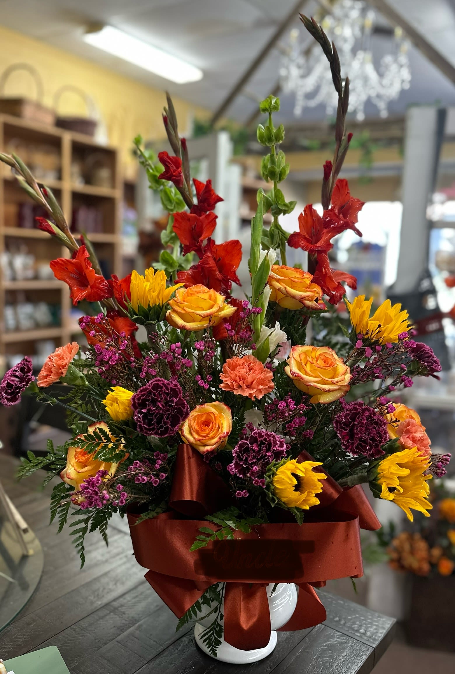 Radiant Fall  - Red gladiolus, purple and orange carnations, yellow with red tip roses, sunflowers and purple wax flowers