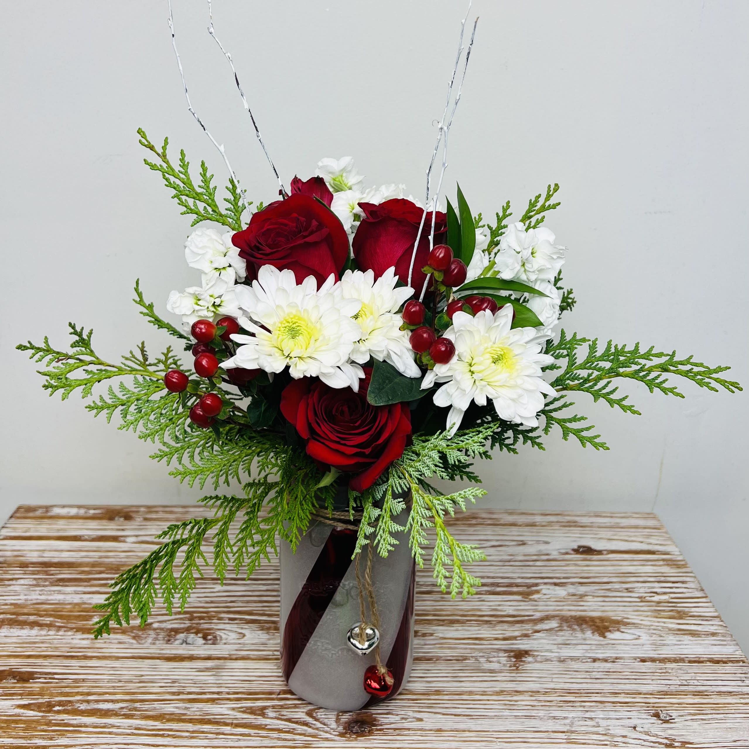 Candy Cane Lane - A candy cane mason jar vase with jingle bells filled with festive reds and whites, winter greens and topped off with white twig accents. Perfect for sending some holiday cheer!