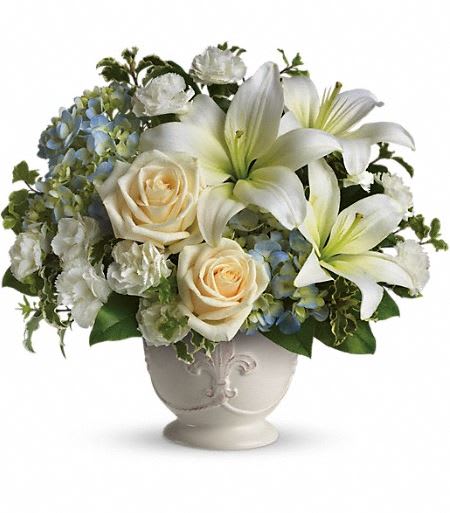 T209-1A Beautiful Dreams by Teleflora - Soothing and respectful. Calm and compassionate. This beautiful collection of white and light colored blossoms will deliver your loving thoughts perfectly. Tasteful flowers such as light blue hydrangea, crème roses, white asiatic lilies, miniature carnations and more are delivered in a lovely white French Country Pot. Approximately 13&quot; W x 12&quot; H 