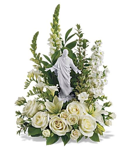 T229-1A Teleflora's Garden of Serenity Bouquet - This exquisite porcelain sculpture of Jesus surrounded by radiant flowers will be a source of comfort to loved ones during a time of loss. Your thoughtfulness will be long remembered. The stunning bouquet includes white roses, stock, snapdragons, lilies and freesia accented with salal, myrtle and pittosporum. Delivered with a meticulously detailed porcelain sculpture of Jesus. Approximately 15 3/4&quot; W x 22&quot; H 