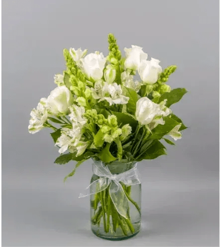 Crisp Whites  - Introducing our elegant Crisp White Floral Arrangement, a timeless blend of sophistication and purity. This stunning arrangement features pristine white snapdragons, delicate white alstroemerias, and velvety white roses, meticulously arranged to create a harmonious display of serenity. Adorned with a subtle touch of refinement, a small white ribbon completes the ensemble. Perfect for any occasion, this all-white floral masterpiece effortlessly radiates grace and beauty. Elevate your space with the purity of Crisp Whites.