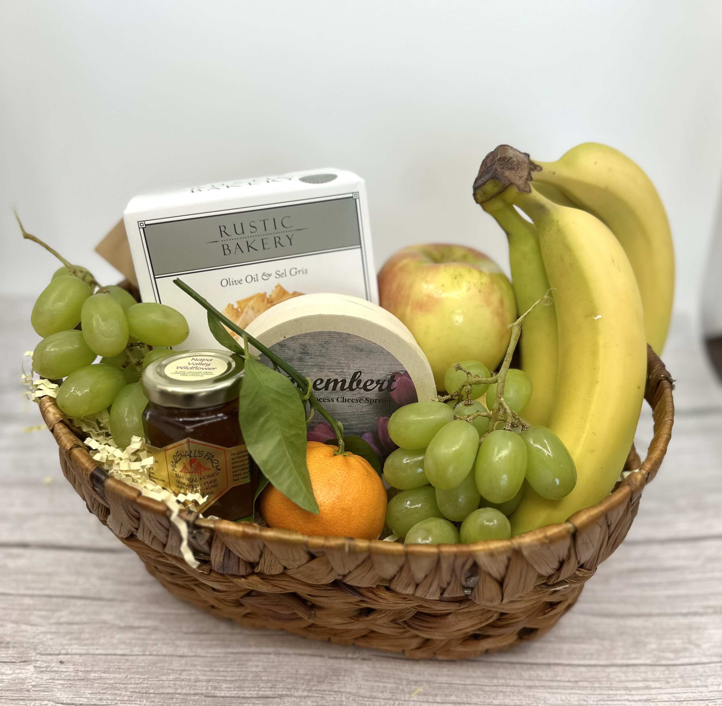 Organic Fruit Basket - Our fruit basket is elevated with Rustic Bakery Crackers, local Napa honey (3oz), and Camembert cheese spread, along with organic fruit in a reusable basket.