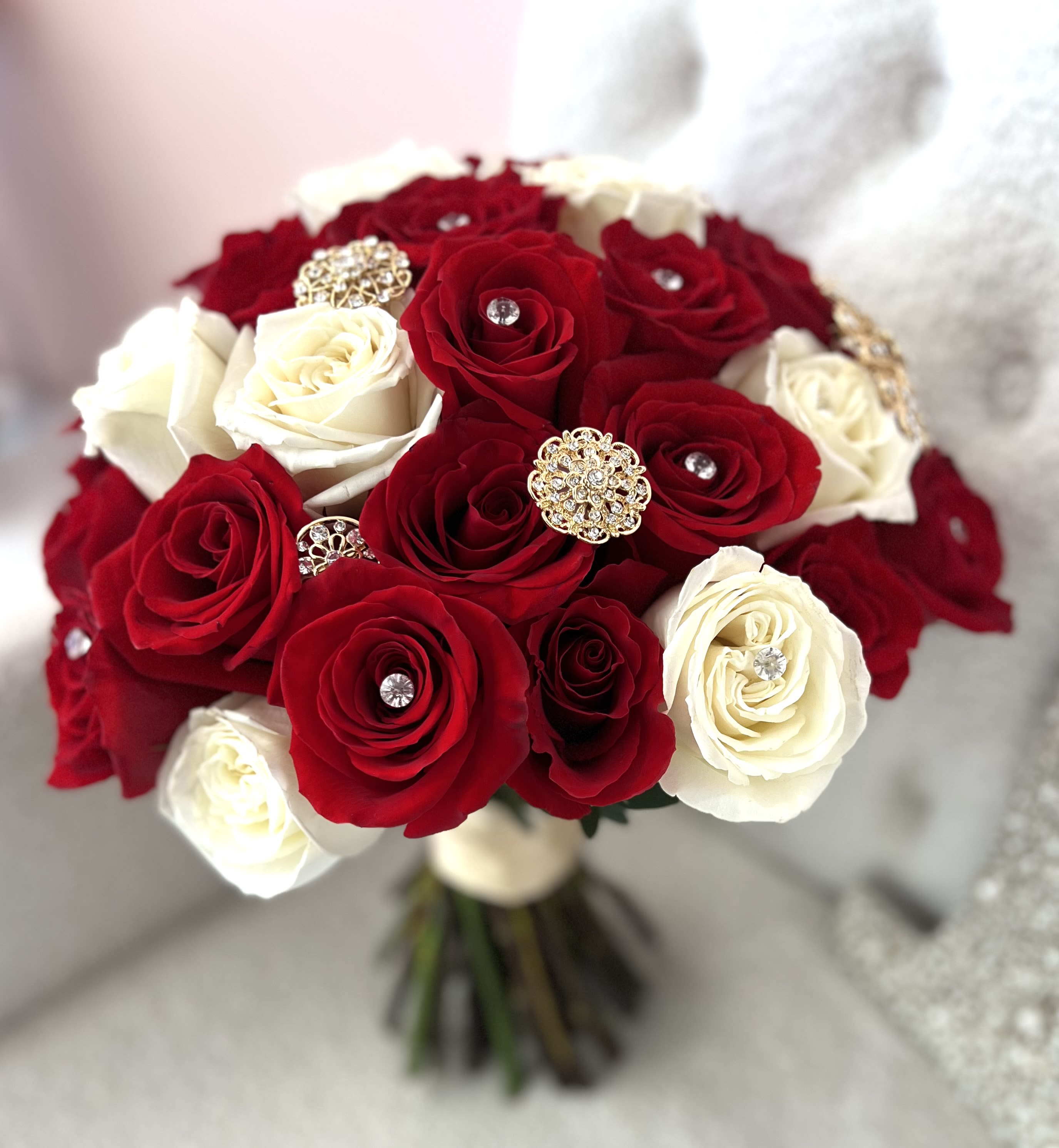 Royal Elegance Bridal Bouquet - A timeless symbol of love and sophistication, our Royal Elegance Bridal Bouquet features a luxurious blend of deep red and creamy white natural roses, hand-tied with care for the modern bride. Each bloom is delicately accented with sparkling rhinestones and vintage-inspired gold brooches, creating an elegant, glamorous look perfect for weddings, engagements, or romantic celebrations. Crafted for those who desire bold beauty and refined charm, this bouquet adds a regal touch to your special day — effortlessly blending tradition with opulence.