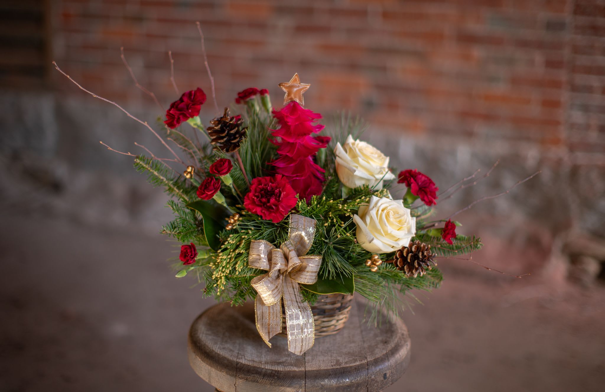Cerise Tree - A decorative and festive tree made from crimson feather with a gold star topper is the focal point of this basket design. The asymmetrical design featured cream, ivory or white roses for contrast. Cherry color flowers encompass the decorative tree. A subtle gold threaded plaid pattern in burlap ribbon gives a hint of glamor in this shabby chic style design. Tree/design(s) are available in wine (as pictured) red and white. Please specify which version we should create in the special instructions.