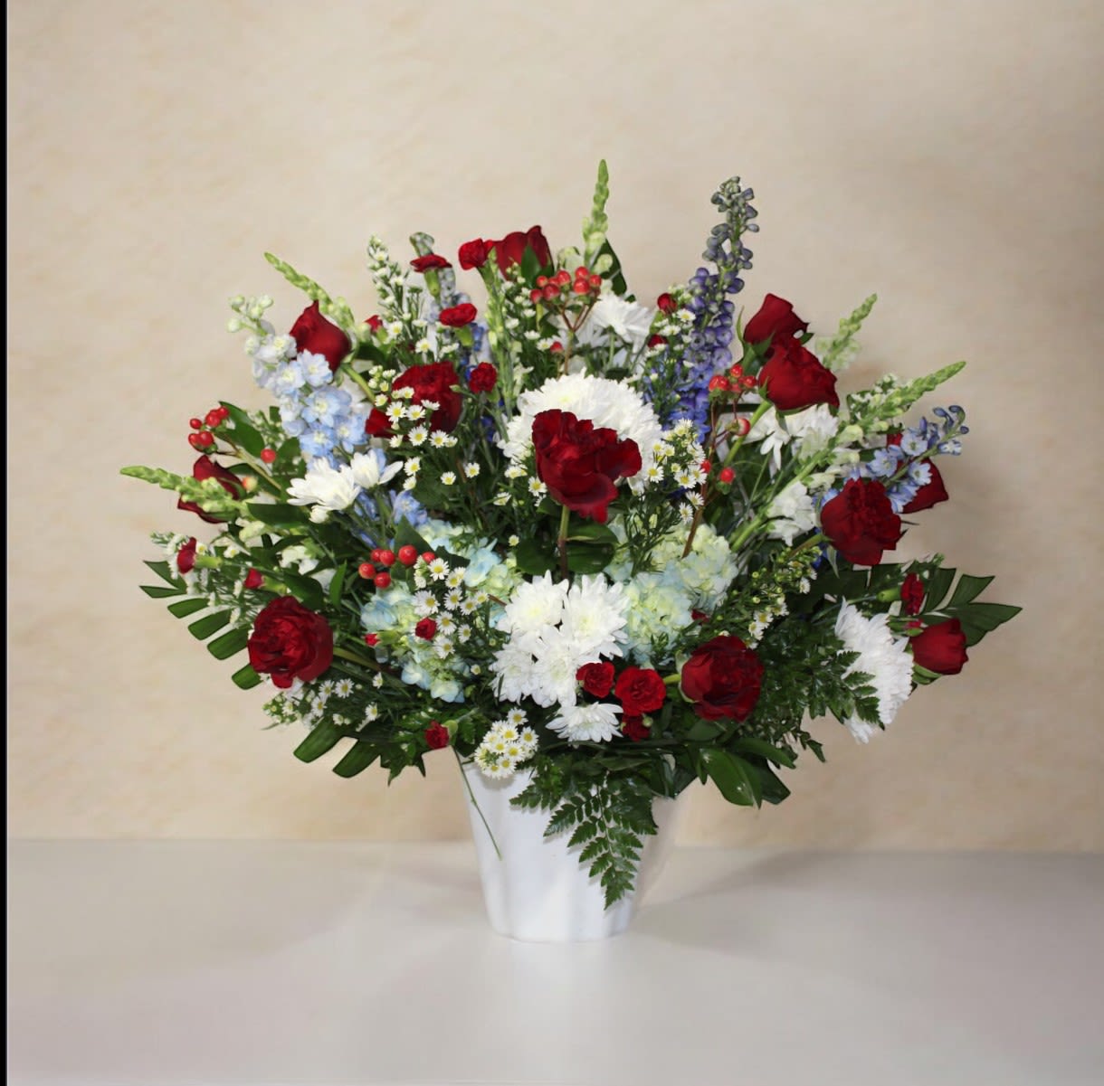 Patriot’s Tribute  - “Patriot’s Tribute” is a stunning red, white, and blue floral arrangement designed to bring elegance, dignity, and a patriotic touch to any altar, ceremony, or special event. Featuring a luxurious combination of premium red roses, white lilies, and blue blooms, this arrangement creates a sophisticated and memorable display perfect for memorials, patriotic events, national celebrations, and high-end altar décor.  Each bloom in “Patriot’s Tribute” is carefully selected by our professional florists to ensure a harmonious, elegant, and long-lasting arrangement. Ideal for anyone searching for red, white &amp; blue altar flowers, luxury floral arrangements, patriotic bouquets, and flowers near me for special occasions.  Locations served: Available for same-day delivery and daily flower service in Manassas, Gainesville, Bristow, and Haymarket, VA.