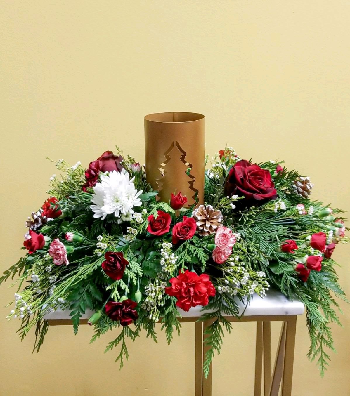 Glowing Christmas Centerpiece - Add blustery cheer to any holiday table with this coniferous centerpiece studded with cardinal–red and white flowers and berries gathered around a glowing candlelit tree lantern.