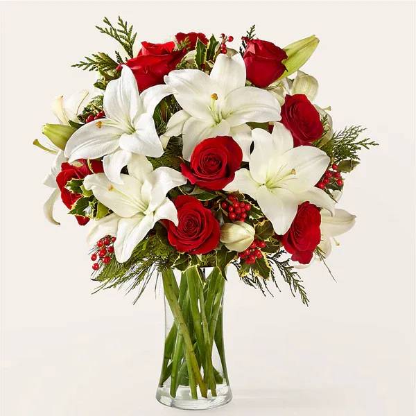 Sparkling Snowflakes Bouquet - Take a wintry stroll with our Sparkling Snowflakes Bouquet, effortlessly capturing the serene beauty of a winter wonderland through a blend of lilies, roses and seasonal greenery.  Details Designed by florists, ready to display. For long–lasting blooms, replace the water daily. We suggest trimming the stems every couple days. Pet Safety Precautions: This bouquet or plant may include flowers and foliage that are known to be toxic to pets. To keep