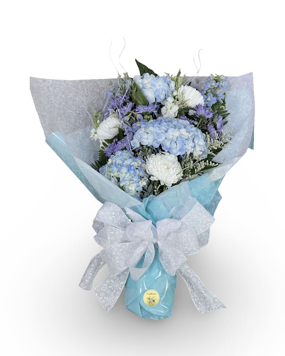 Winter Frost Cellowrap - Wrap your bouquet in winter charm with this beautifully styled cellophane wrap. Soft blue and white tones pair perfectly with the playful winter themed bow, creating a crisp seasonal look that highlights any arrangement. The stems are wrapped in a water soaked sponge to keep the flowers fresh for a few hours. This wrap does not include a vase and should be placed in water once gifted or enjoyed at home.