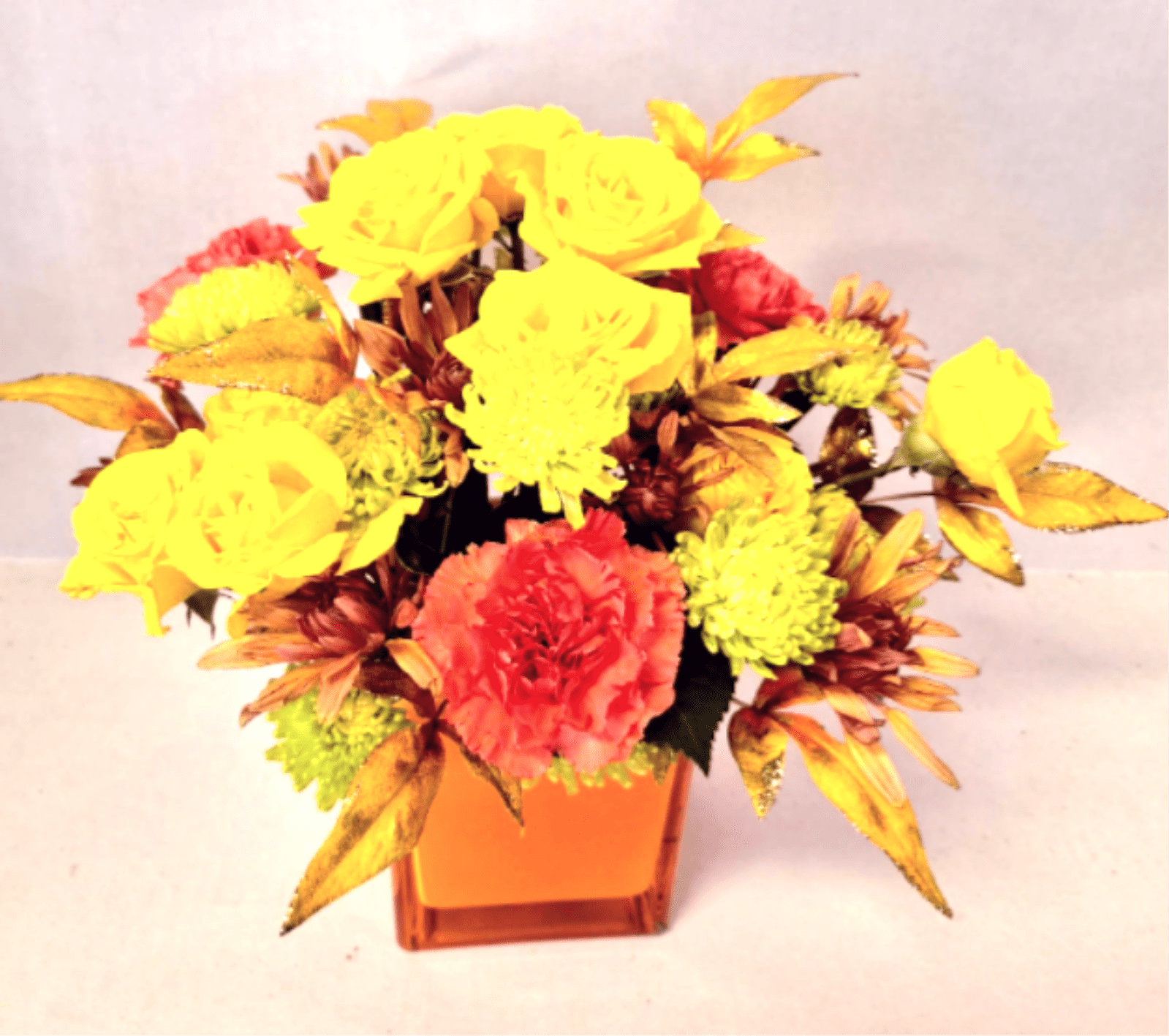 Sweet Fall - A mix of miniature roses, carnations and fall flowers with glittering fll leaves in an orange glass cube.