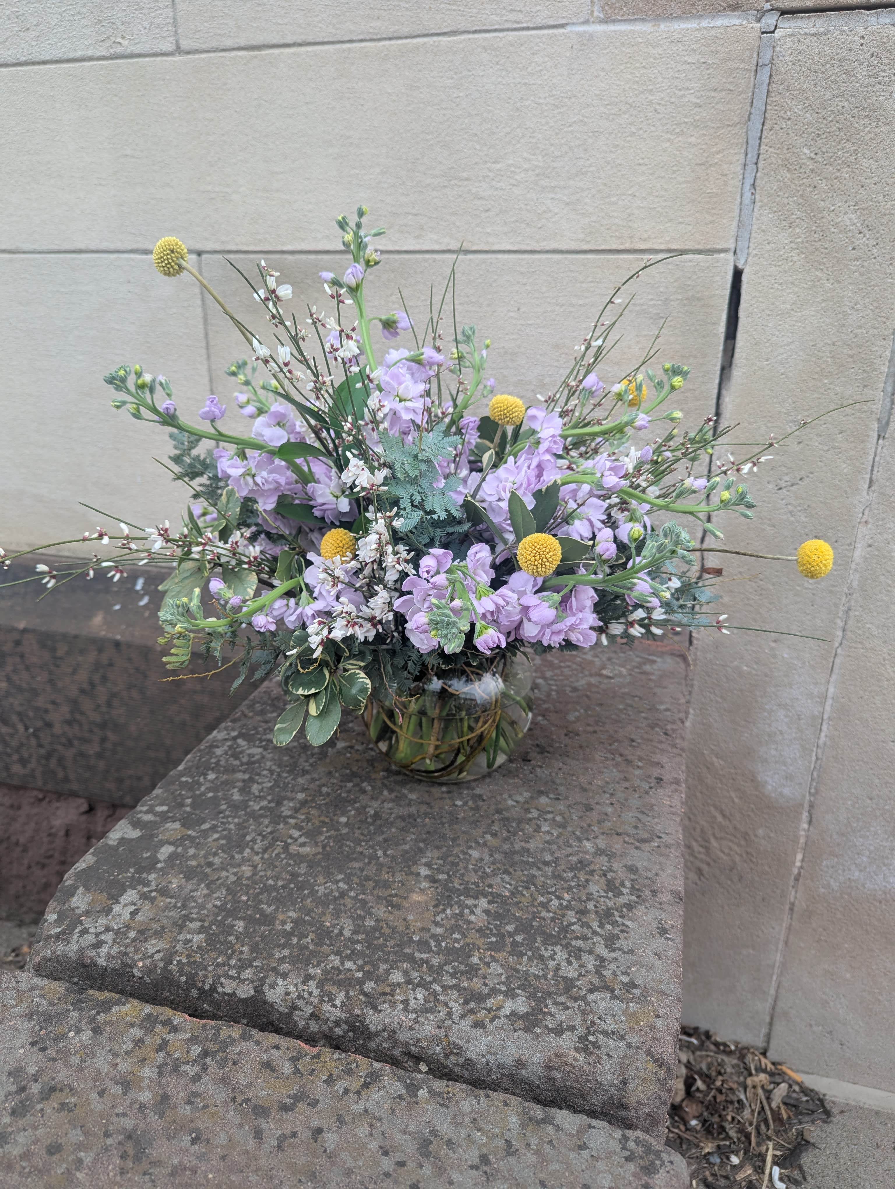 Fragrant Spring - Lush foliage and abundant stems of fragrant stock. Yellow craspedia add a whimsical pop. 