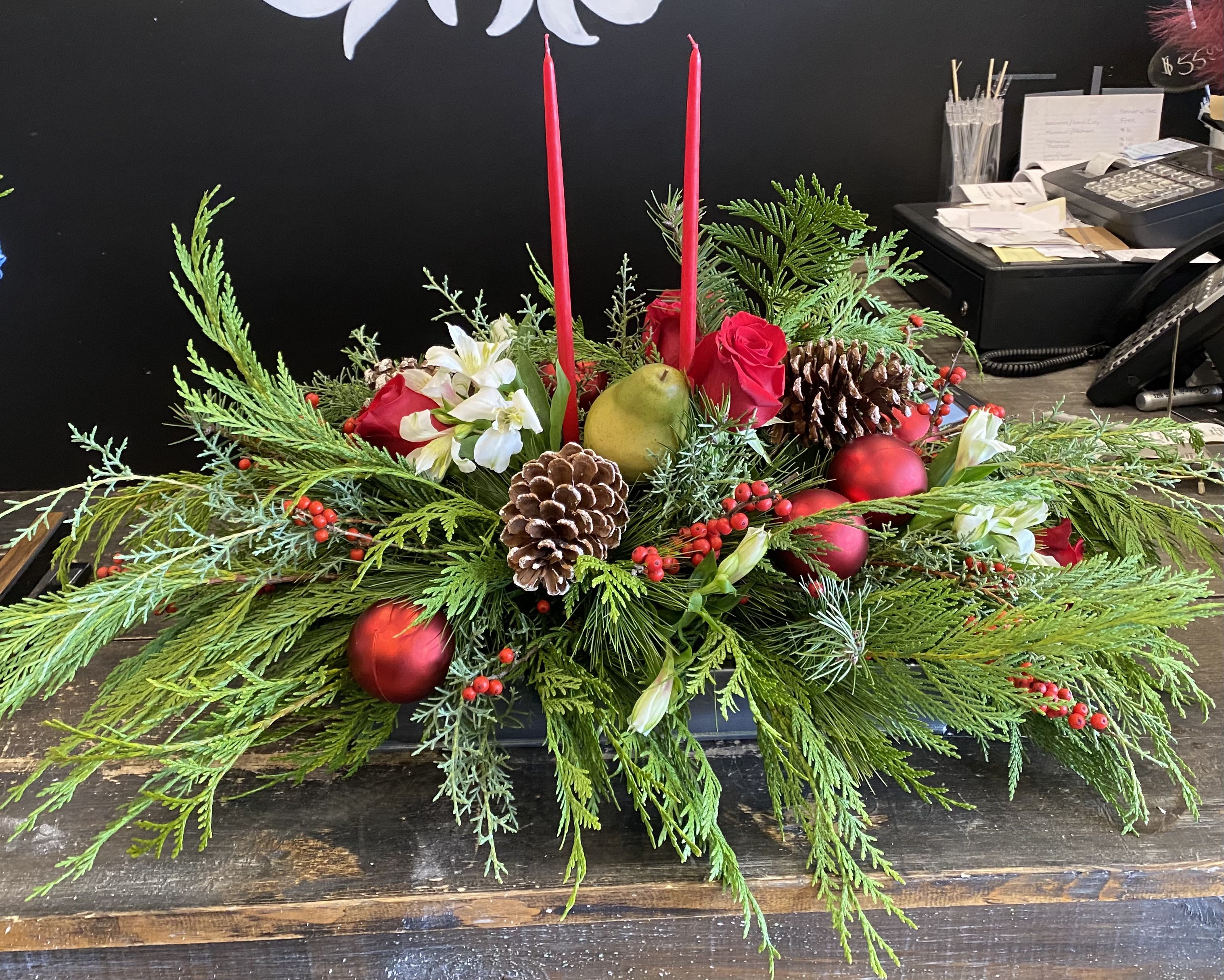 Home for the Holidays  - An enchanting table centerpiece with premium hand dipped candles, aromatic seasonal greens, red roses and festive embellishments