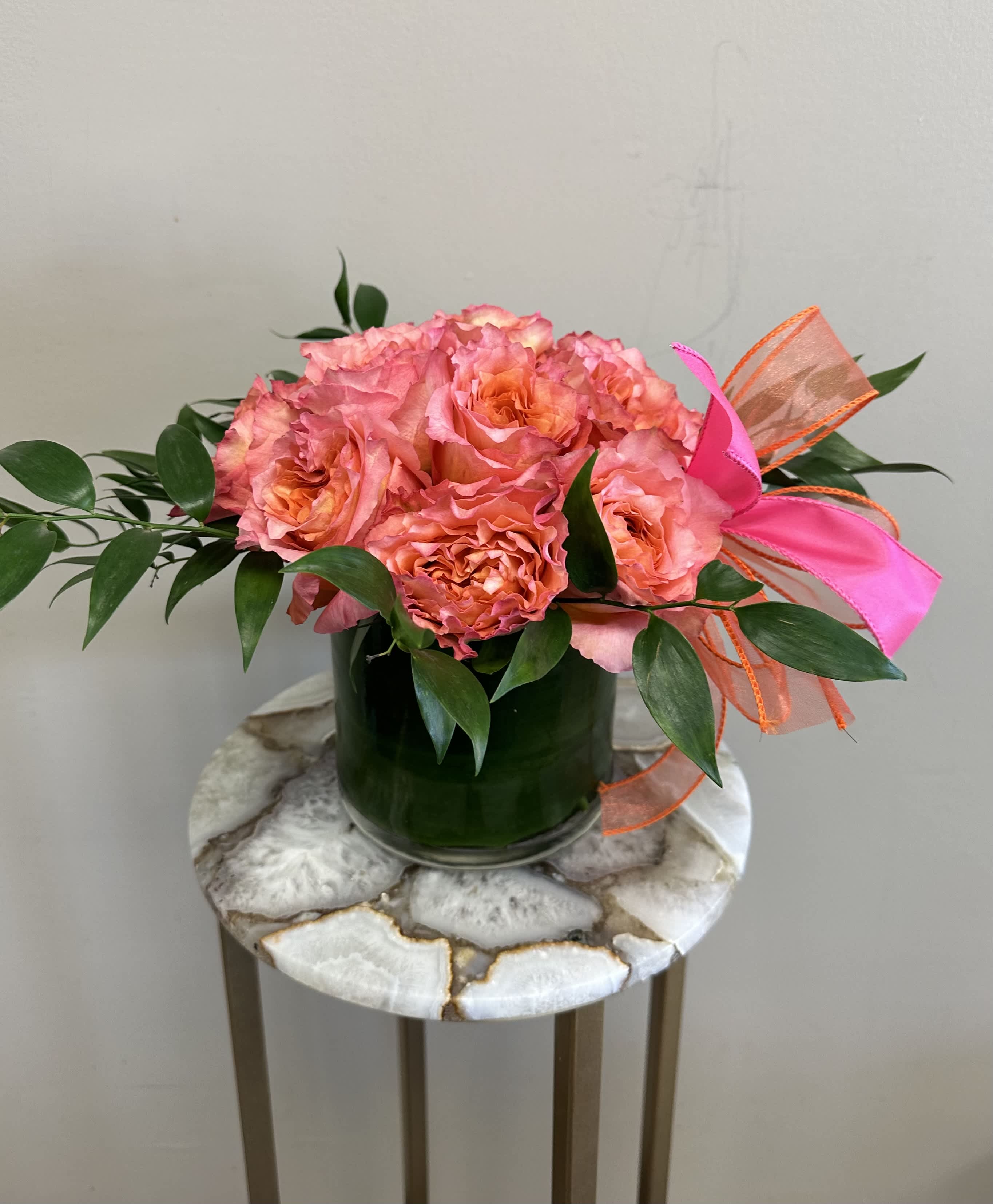 Spring Sunset - A dozen free spirit roses in a modern styled shorter vase with greenery around the sides. These roses are the perfect gift for anniversaries, birthdays, retirement, or even just because! Order for a same day or next day delivery and give us a call if you want custom flowers. 